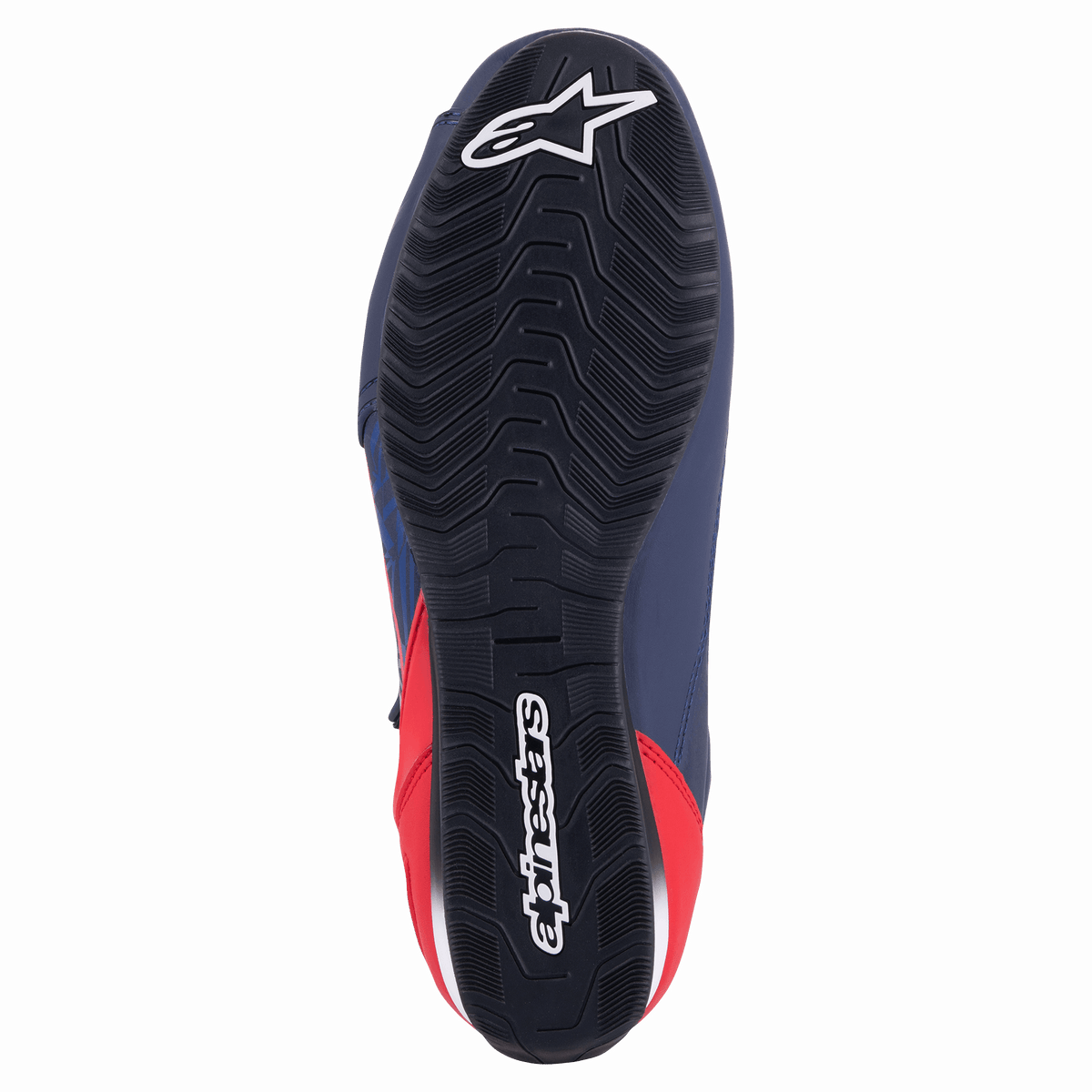 Chaussure de moto Alpinestars Austin, bleu marine et rouge vif, vue de dessous montrant la semelle extérieure en caoutchouc noir avec adhérence texturée ondulée et marquage Alpinestars blanc