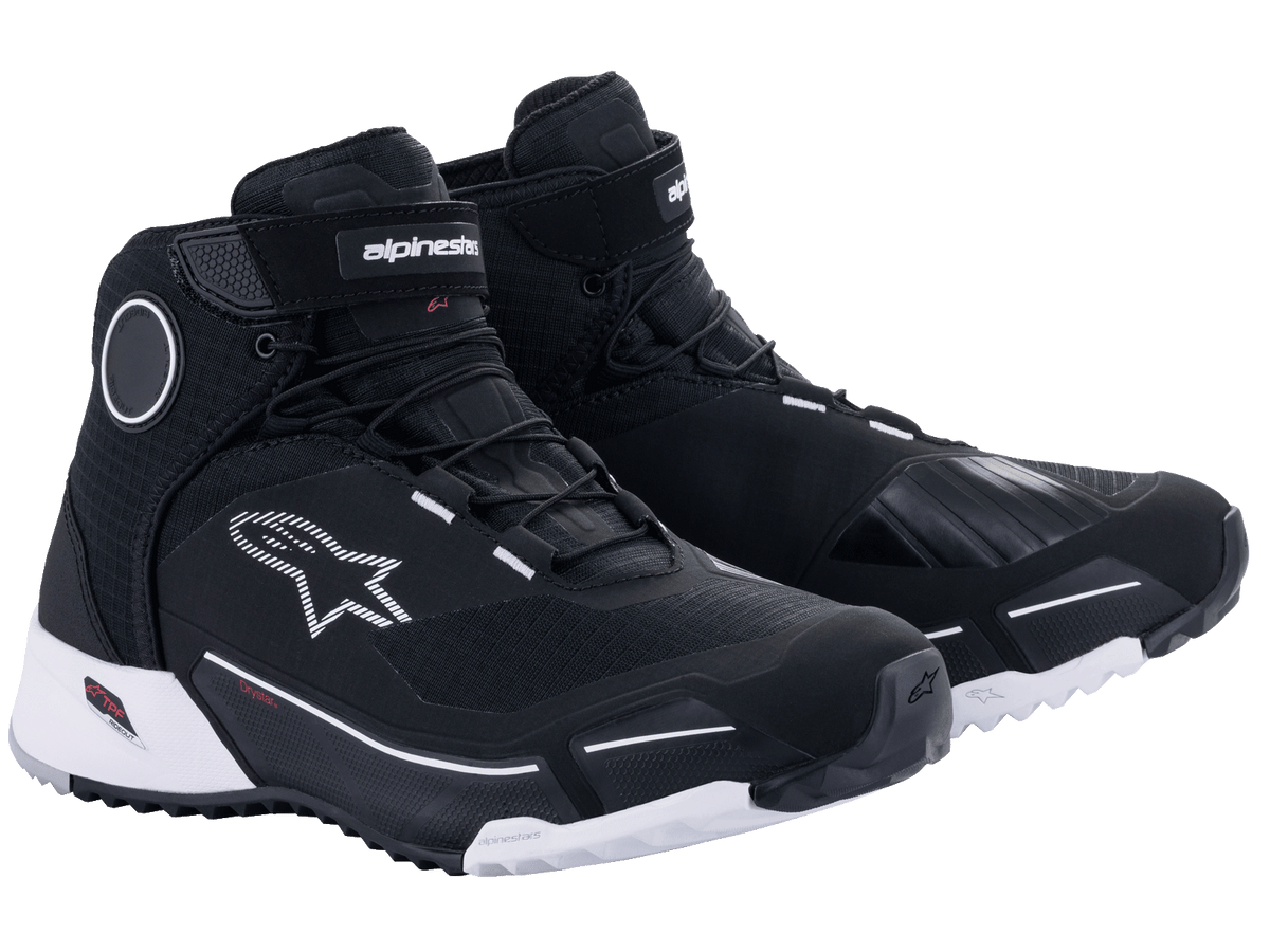 Chaussures de moto Alpinestars CR-X Drystar en noir et blanc, chaussures de moto imperméables de style sportif dotées d'une semelle extérieure blanche, tige en textile noir avec accents de logo blancs et disques de protection aux chevilles.