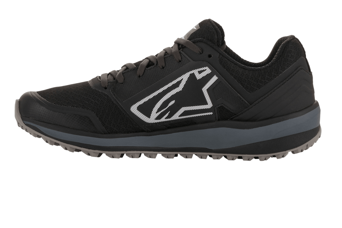 Chaussures Alpinestars Meta Trail, chaussure de course performante, noir et gris foncé, profil latéral avec grand logo Astars blanc, semelle intermédiaire gris foncé, semelle en caoutchouc crantée résistante à l'huile, conçue pour le confort des paddocks et des équipes de sport automobile
