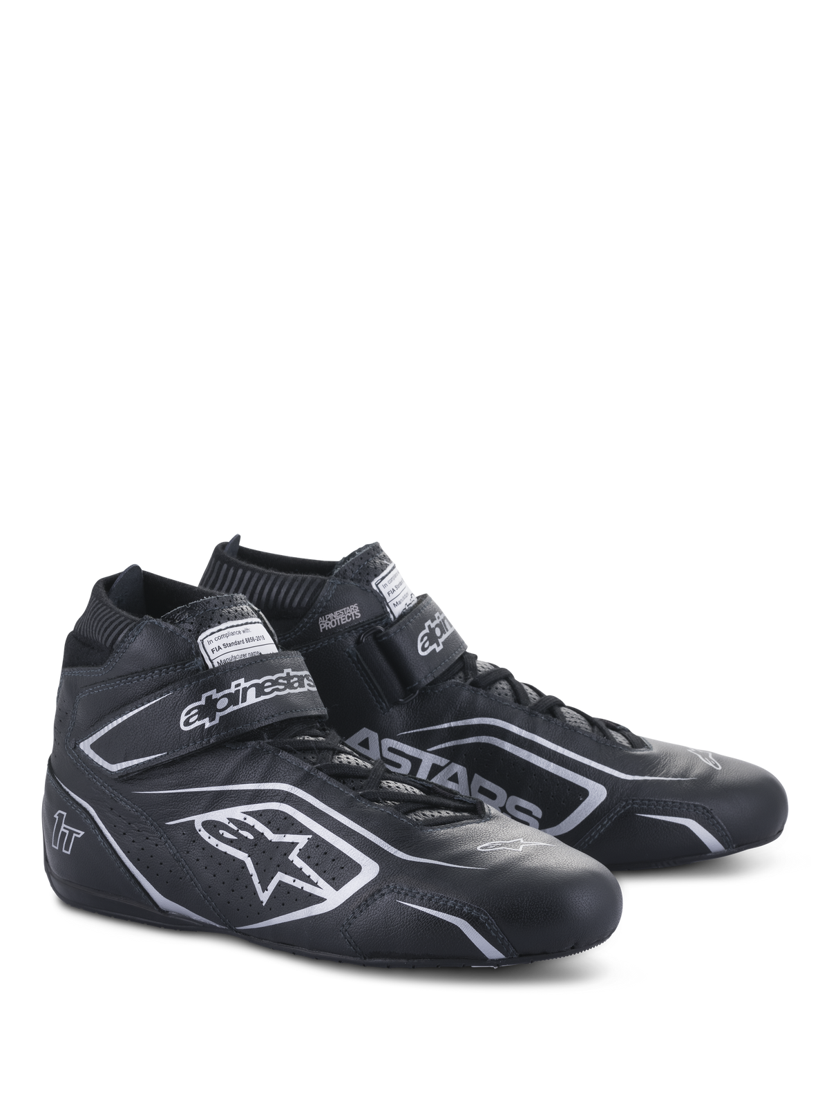 Chaussures Alpinestars Tech-1 T V3 FIA, chaussures de course automobile, noir et argent, construction en cuir de bovin avec logos et marquages Alpinestars argentés, vue latérale inclinée avec sangle auto-agrippante et fermeture à lacets