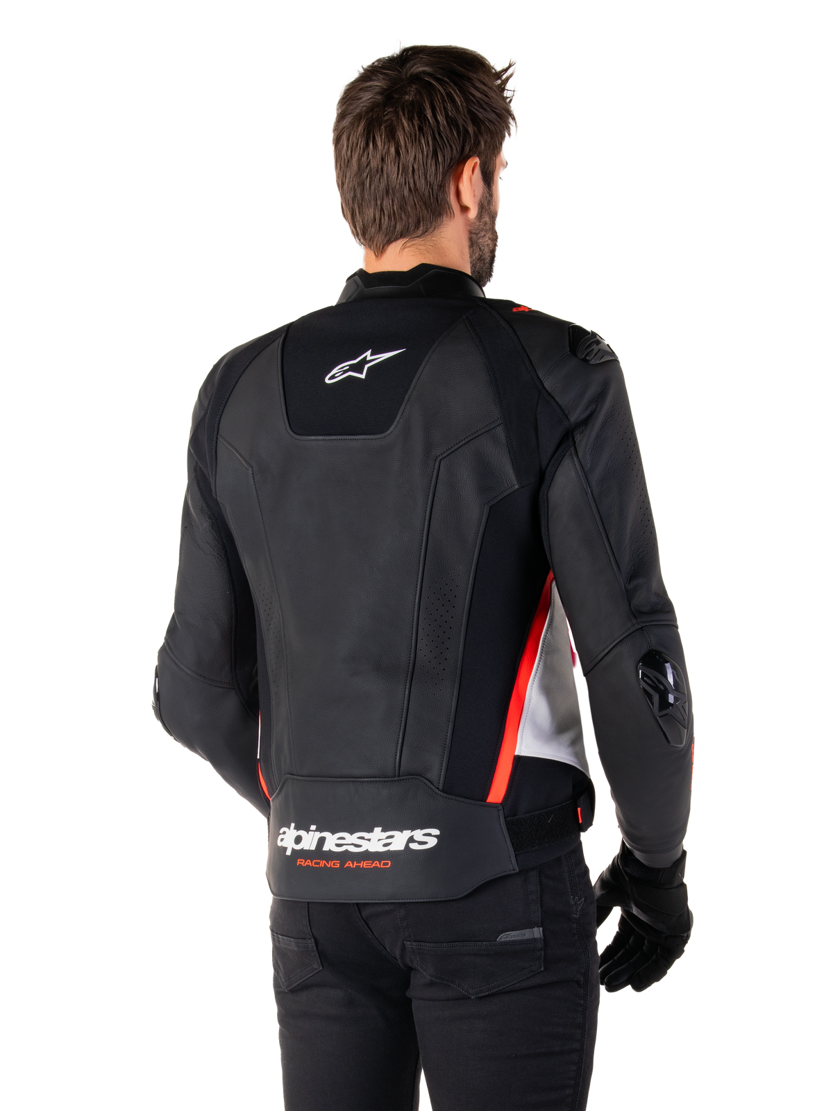Veste en cuir Alpinestars Missile V3, vue de dos sur un motard, noir, blanc et rouge fluo, avec logo Alpinestars et texte « RACING AHEAD » au bas du dos, construction en cuir premium avec panneaux extensibles techniques et sliders de protection en TPU, portée avec des gants et un pantalon noirs.