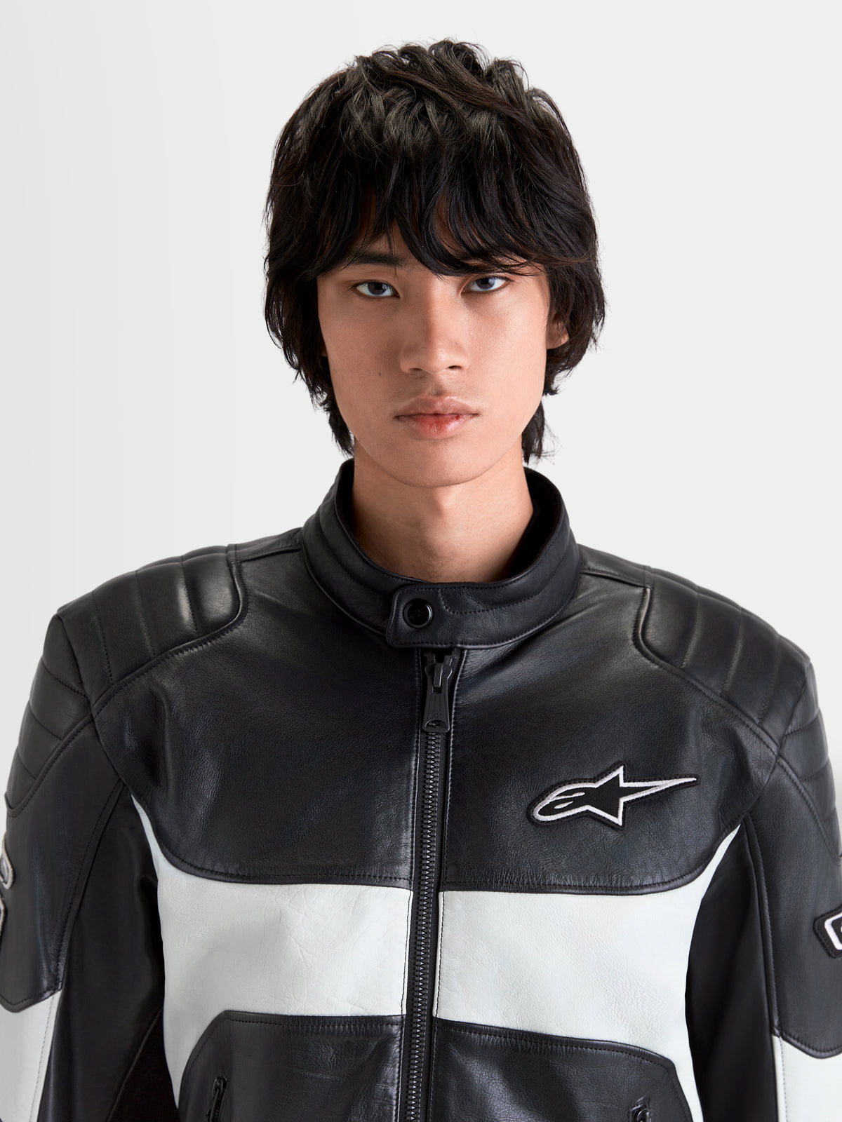 Alpinestars Revern Veste en cuir, blouson de moto urbain pour homme noir et gris métal, vue de face rapprochée sur un modèle montrant la construction en cuir pleine fleur, le col motard et le logo Alpinestars blanc
