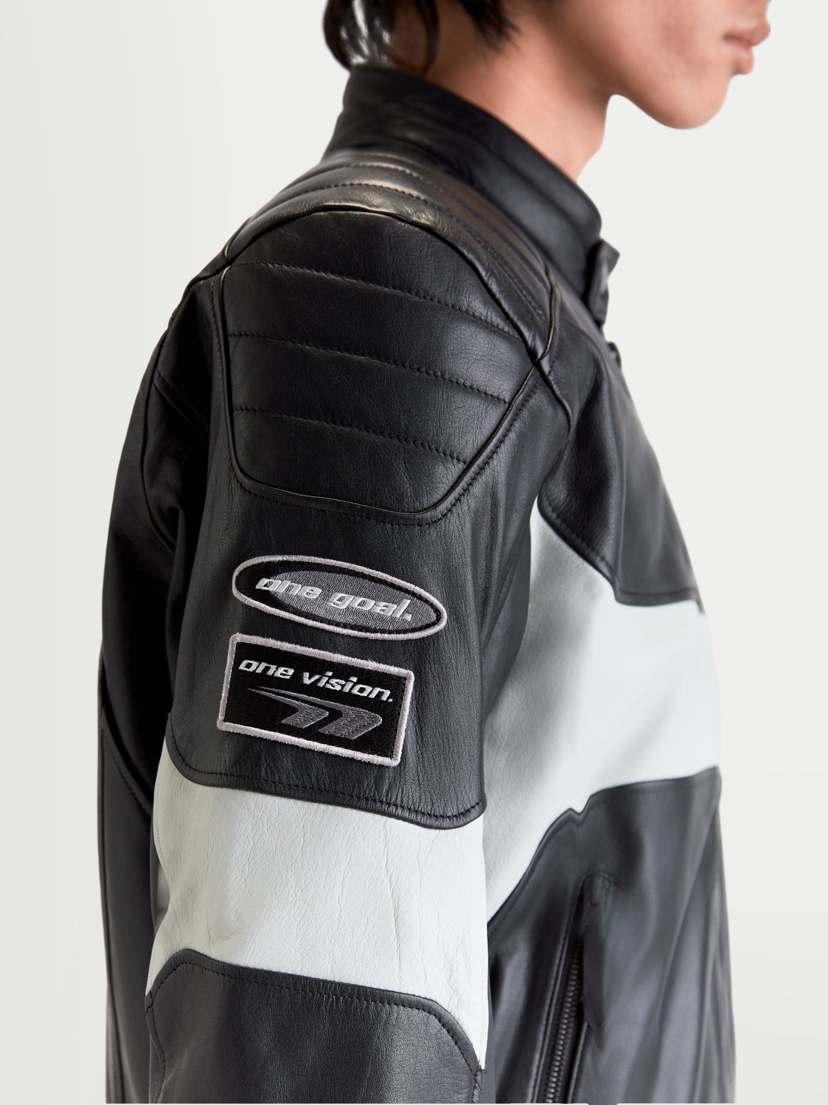 Alpinestars Revern Veste en cuir, blouson de moto urbain pour homme noir et gris métal, vue rapprochée de profil montrant les écussons d'inspiration vintage sur la manche et la construction en cuir vieilli portée par un modèle