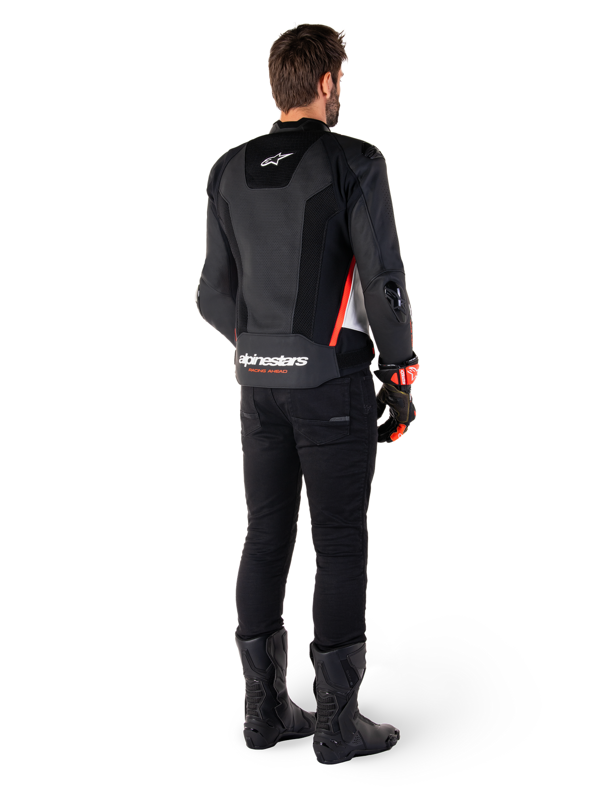 Motard vu de dos portant la veste en cuir Alpinestars Missile V3 Airflow en Noir Blanc Rouge Fluo, assortie d'un pantalon noir et de bottes noires, avec cuir perforé pour la ventilation, protections d'épaules DFS et logo Alpinestars distinctif sur le bas du dos.