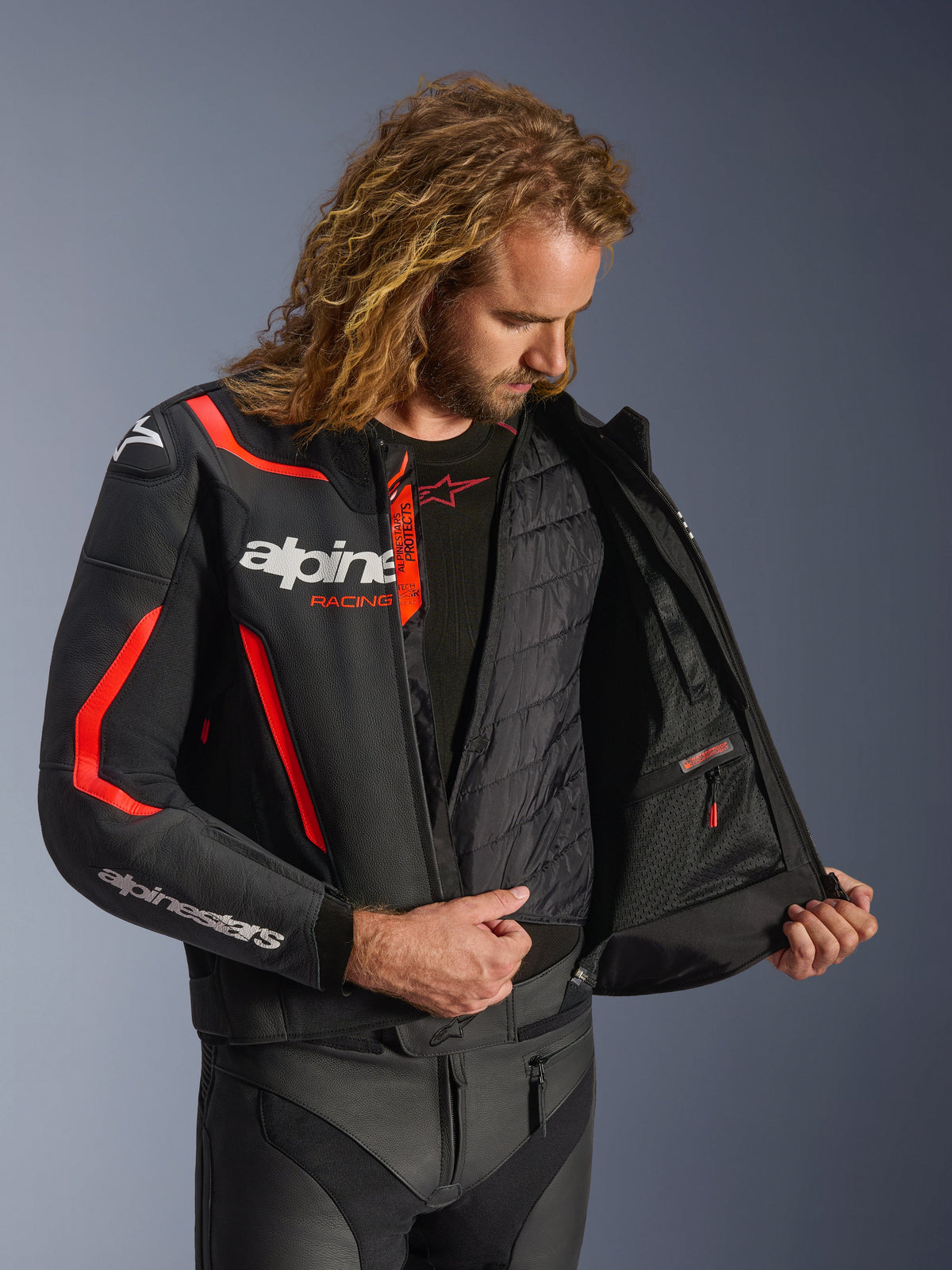 Blouson en cuir Alpinestars GP Force V2 en Noir et Rouge Fluo, vue intérieure détaillée sur modèle montrant le gilet thermique amovible et la poche intérieure imperméable, construction en cuir premium pour la protection en conduite sportive