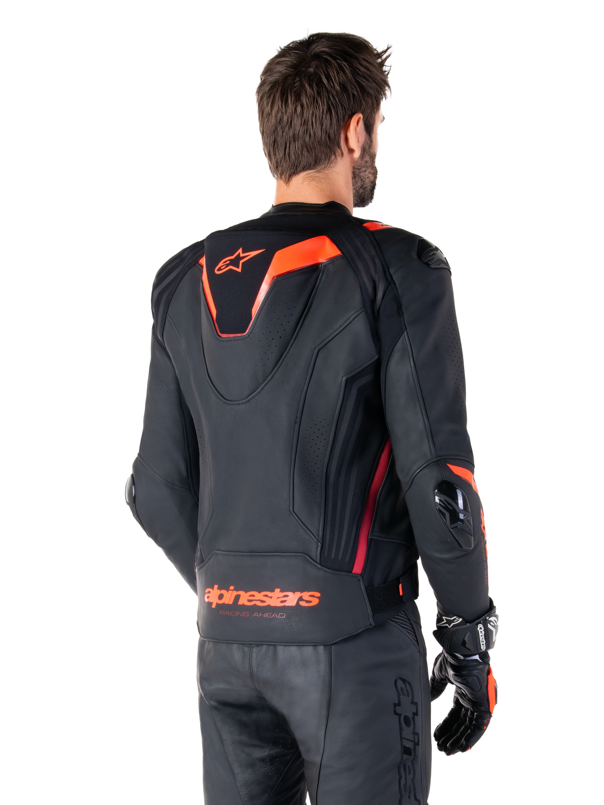 Veste en cuir Alpinestars Missile V3 Ignition, veste de sport de course pour homme, noir avec accents rouge fluo, vue de dos présentant la bosse aérodynamique sport profilée et le logo Alpinestars sur le bas du dos, portée avec un pantalon en cuir noir et des gants de course, design motorsport professionnel et épuré