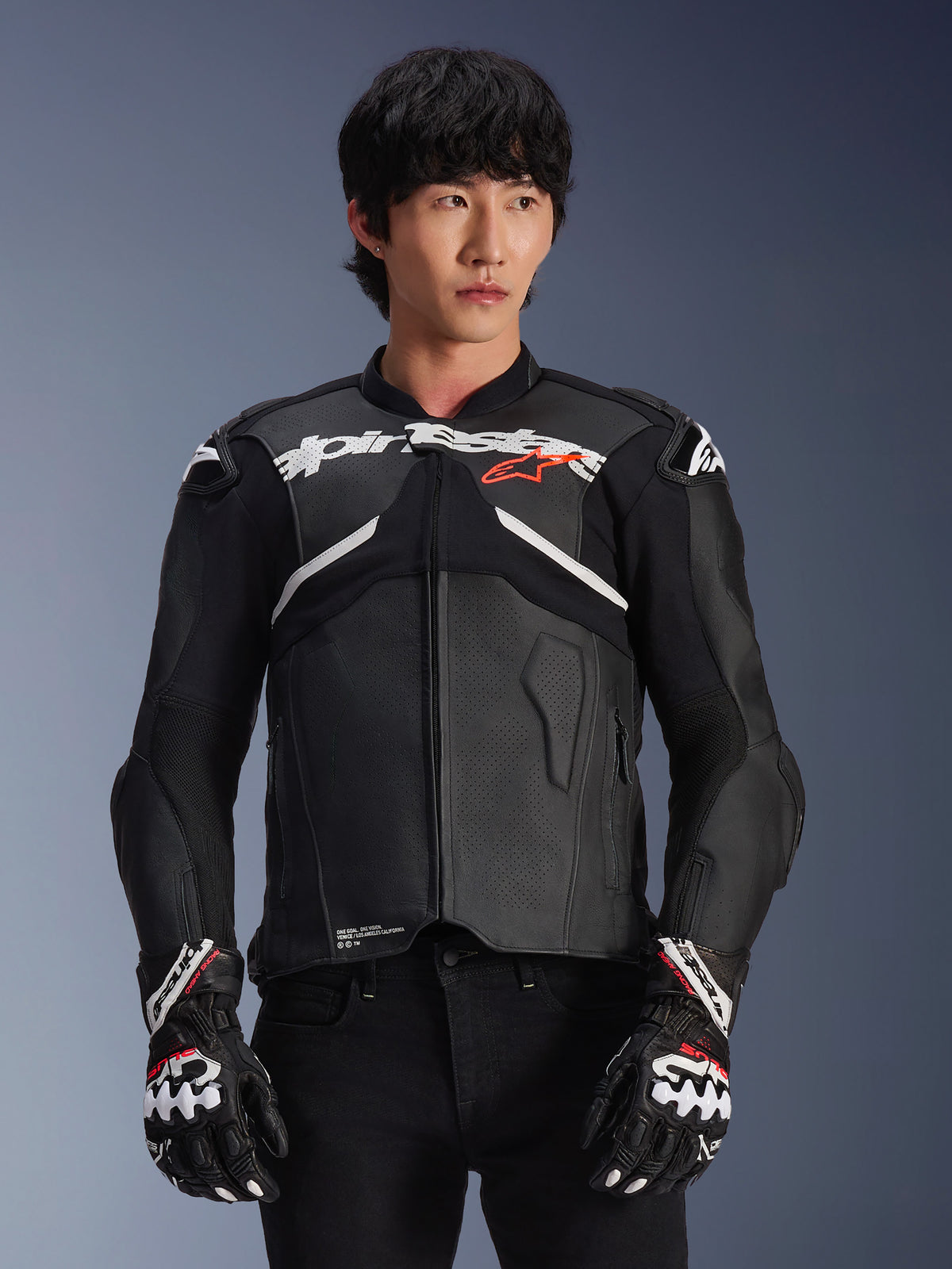 Veste en cuir Alpinestars Atem V5, veste de course de moto, noire avec des accents blancs et rouges, construction en cuir premium avec protections renforcées, portée avec des gants de course assortis