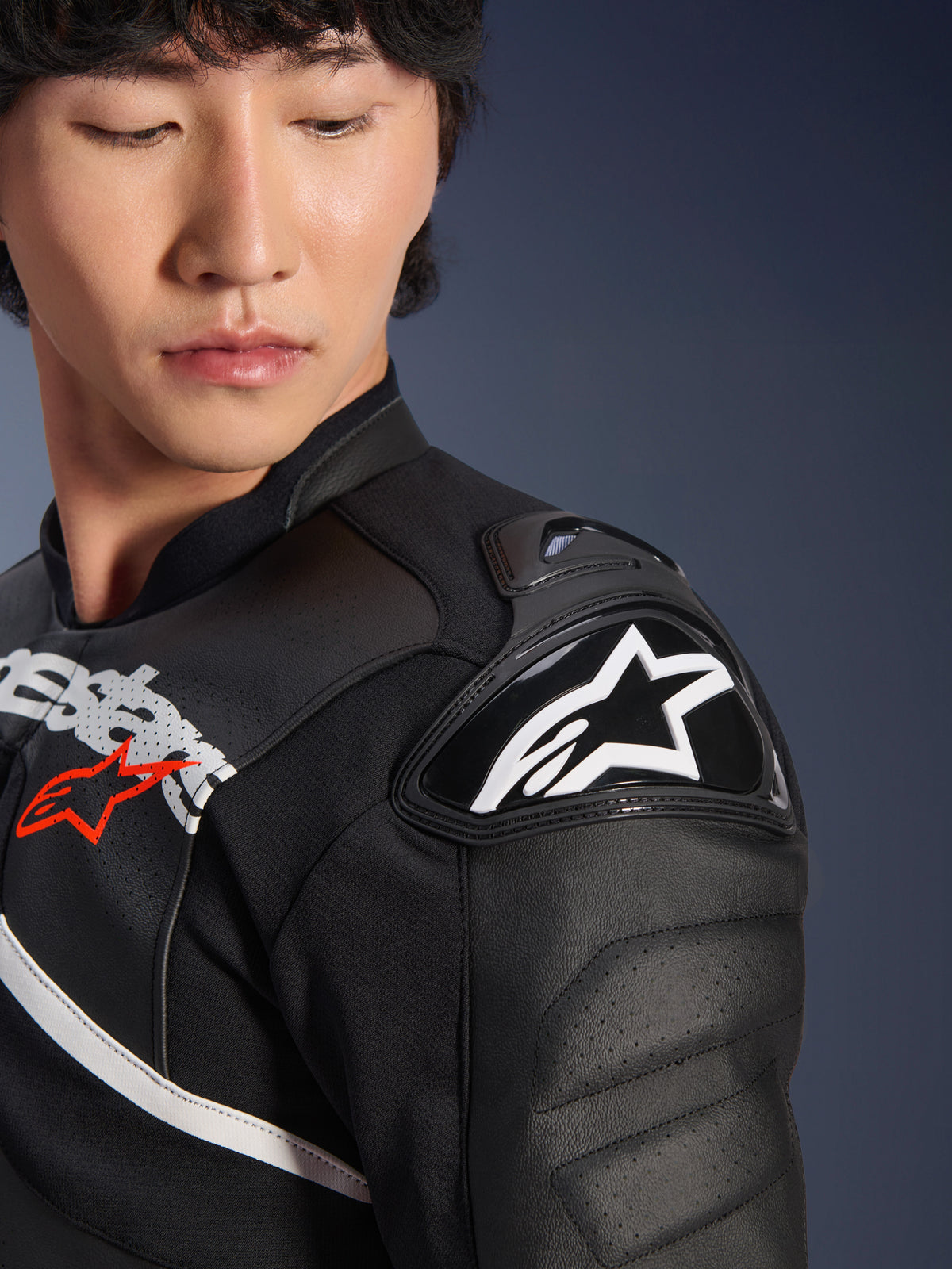 Gros plan sur la veste en cuir Alpinestars Atem V5 en noir et blanc, présentant la protection d'épaule DFS RR avec logo étoile blanc, une construction en cuir perforé et des graphismes sur la poitrine inspirés de la course.