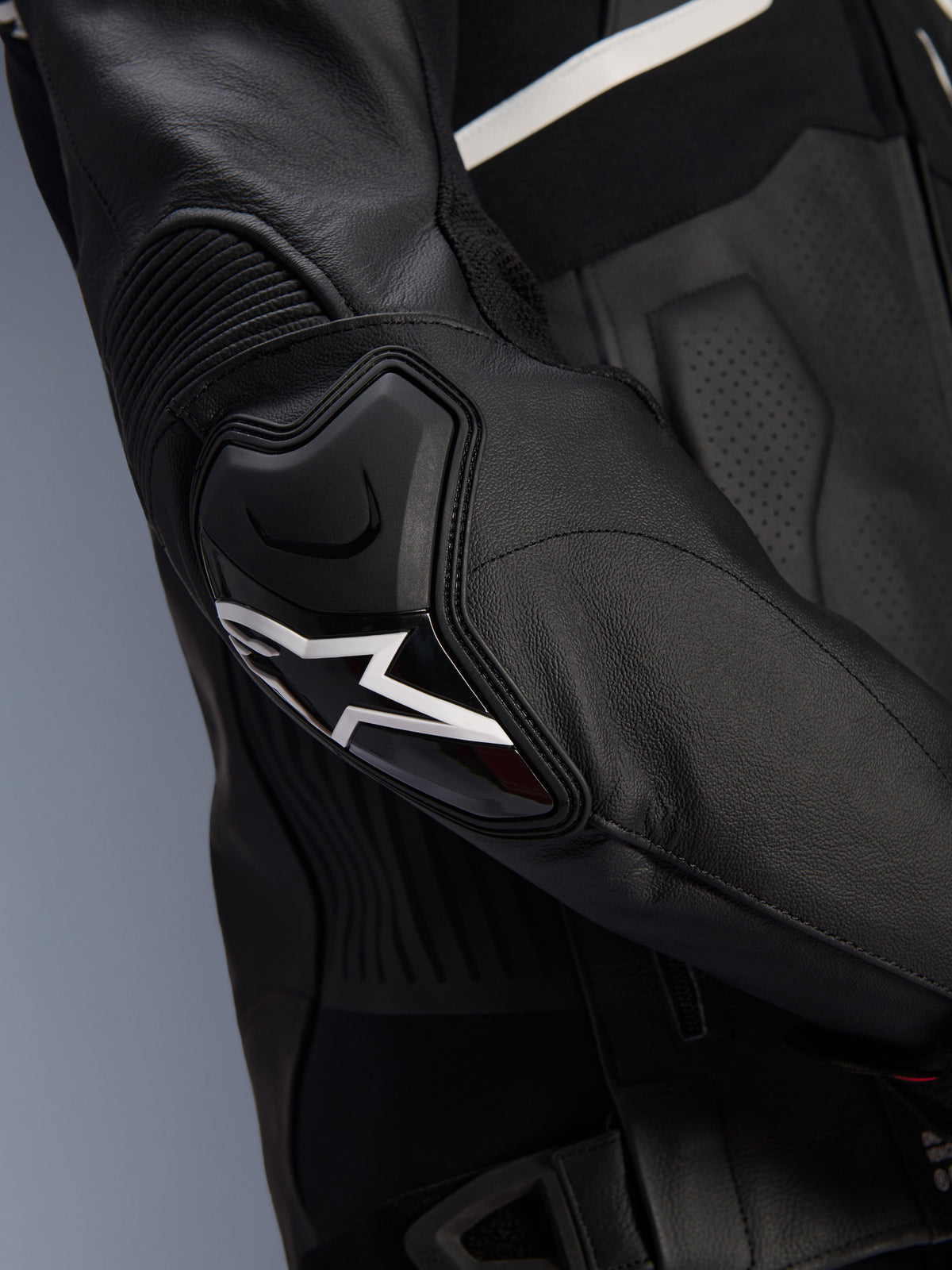 Veste en cuir Alpinestars Atem V5, noir et blanc, gros plan sur la protection de coude DFS RR avec logo étoile blanc, dotée de cuir en accordéon et de textures perforées pour une conduite sportive