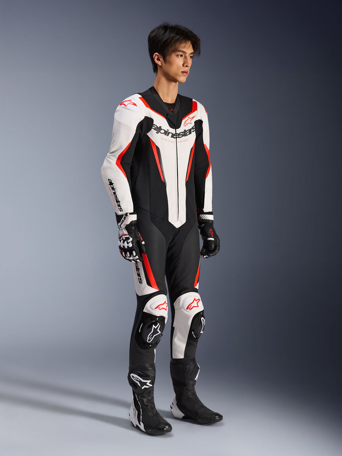 Alpinestars GP Force V2 Leather Suit - 1Piece, combinaison de course de moto une pièce, Blanc, Noir et Rouge Fluo, portée avec des gants et des bottes assortis, avec du cuir perforé et le logo Alpinestars bien visible, design aérodynamique pour la performance sur piste