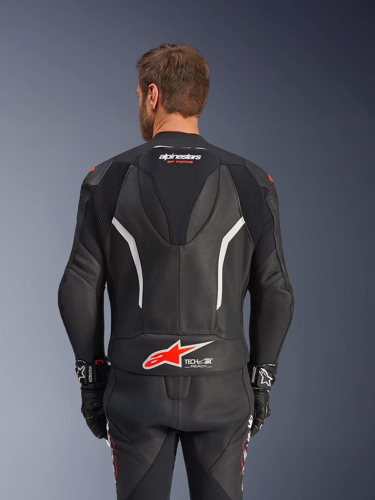 Combinaison en cuir Alpinestars GP Force V2 - 2 pièces, noir, blanc et rouge fluo, vue de dos de la veste en cuir, avec logo Tech-Air Ready, accents blancs, panneaux en cuir perforé et soufflets d'aisance en accordéon pour la mobilité.