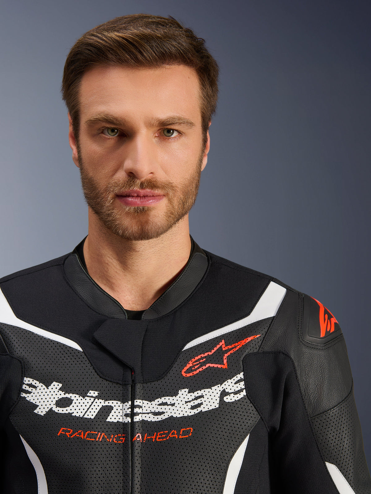 Veste de combinaison en cuir Alpinestars GP Force V2 2 pièces, noir, blanc et rouge fluo, portrait en gros plan présentant du cuir perforé, marquage Alpinestars blanc et texte rouge 'RACING AHEAD', équipement de moto haute performance
