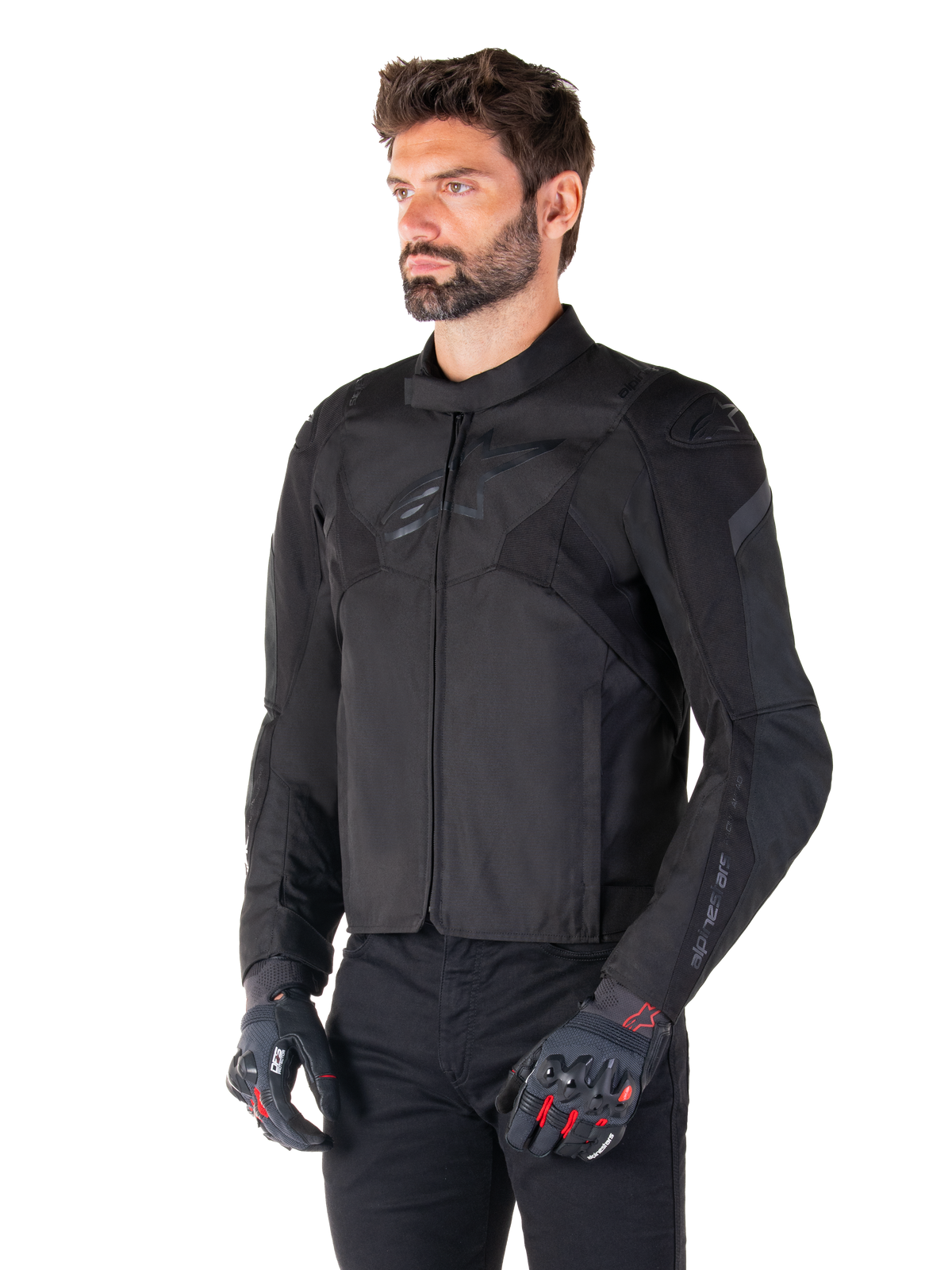 Motard portant la veste imperméable Alpinestars T-Jaws V4 en Black Black, associée à un pantalon noir et des gants de protection, avec une coupe sport épurée, des logos Alpinestars ton sur ton sur la poitrine et les épaules, et une construction textile haute performance.