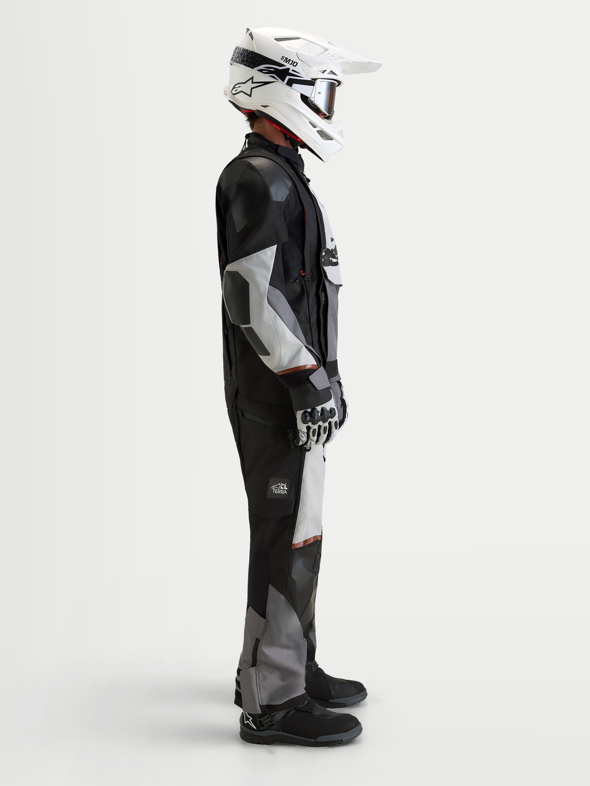 Alpinestars Harok V 2 Drystar Veste, veste de moto adventure pour homme, gris foncé, gris glacier et noir, portée avec un casque blanc et un équipement de moto tout-terrain en vue de profil en studio