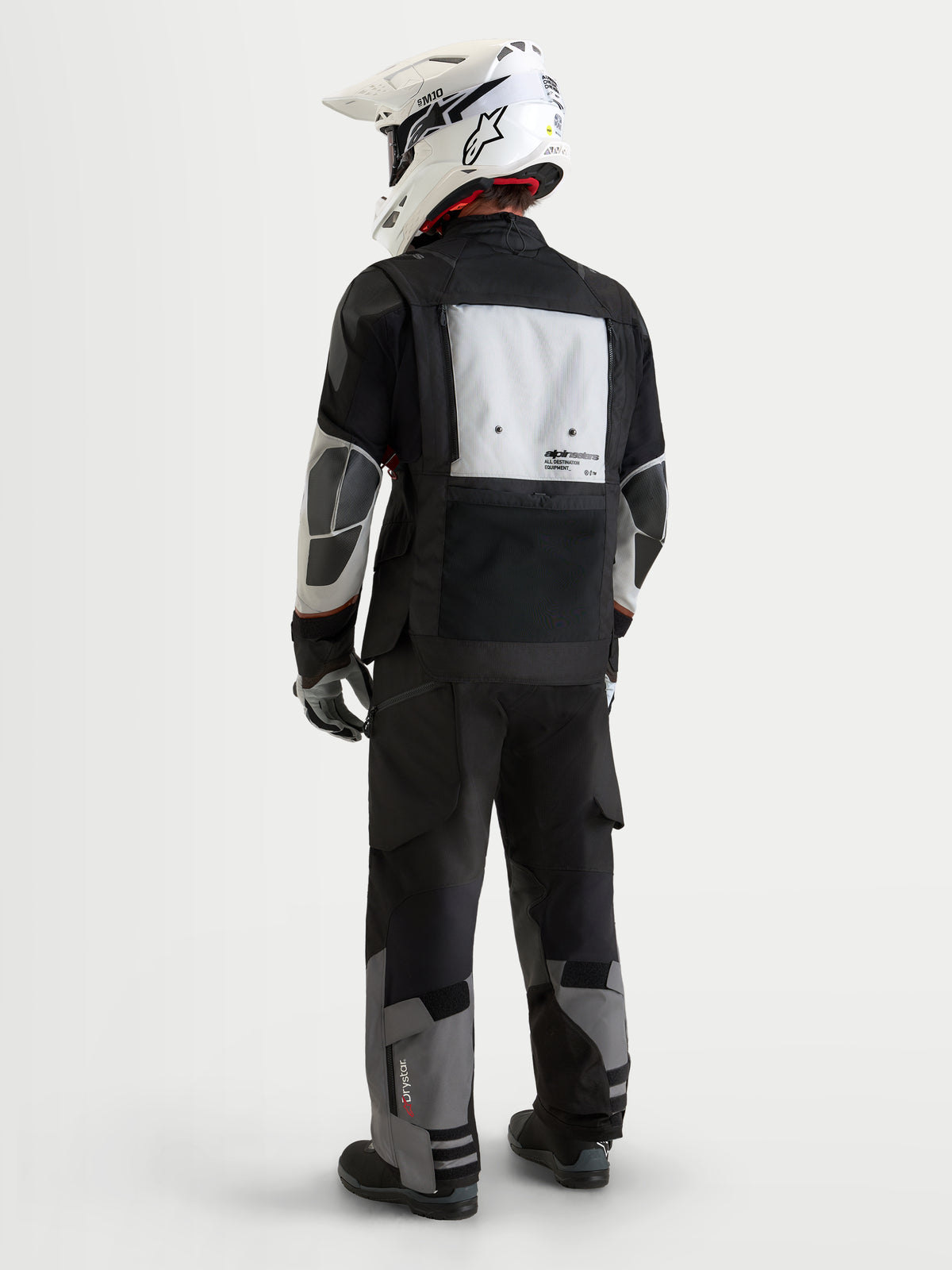Harok V 2 Drystar Veste d'Alpinestars, veste moto d'aventure pour homme, gris foncé, gris glacier et noir, vue de dos montrant le panneau de ventilation modulaire, les zones de renfort en PU et un casque tout-terrain blanc