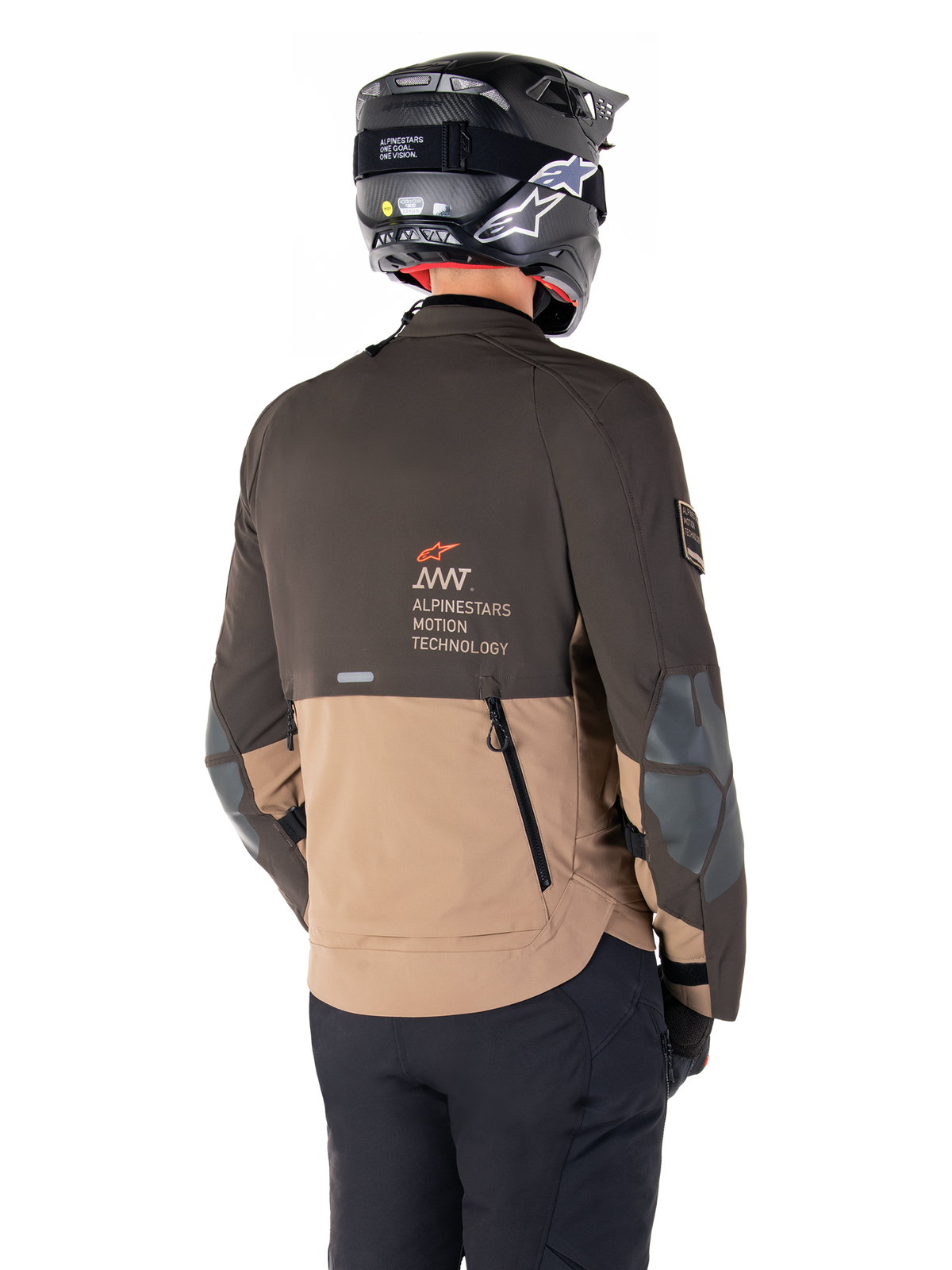 Veste Alpinestars AMT-8 Stretch Drystar® XF, veste de moto d'aventure, brun foncé et kaki foncé, vue arrière montrant le marquage AMT Alpinestars Motion Technology, design textile bicolore avec fermetures éclair de ventilation à l'arrière et échappement en bardeaux, portée avec un casque noir et un pantalon de moto