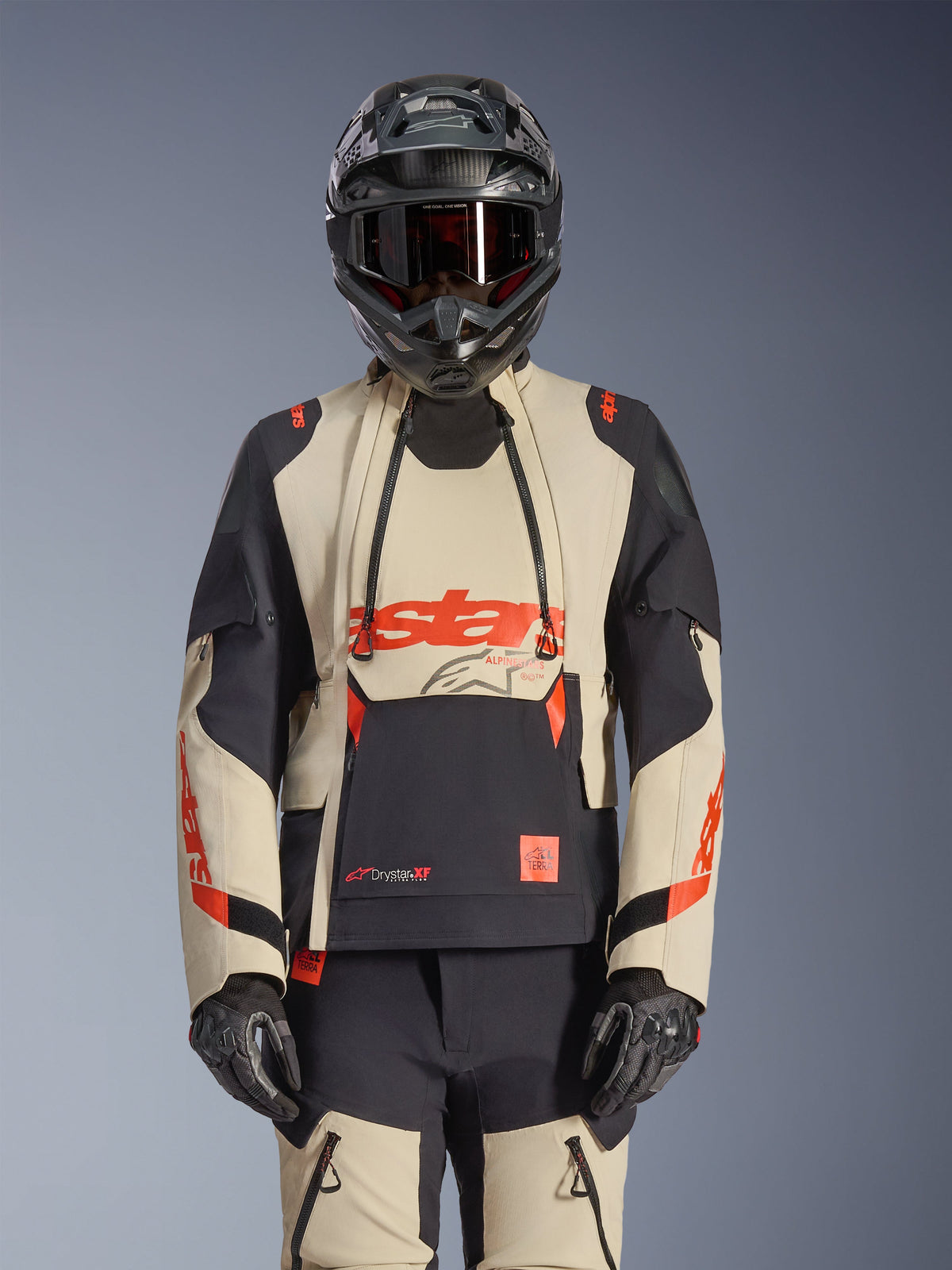 Veste Alpinestars Halo Pro Drystar XF Laminated, veste de moto d'aventure en Mastic Black et beige avec accents rouges, portée avec un équipement de protection complet incluant casque et gants, dotée de panneaux de ventilation modulaires et d'une construction laminée 3L.