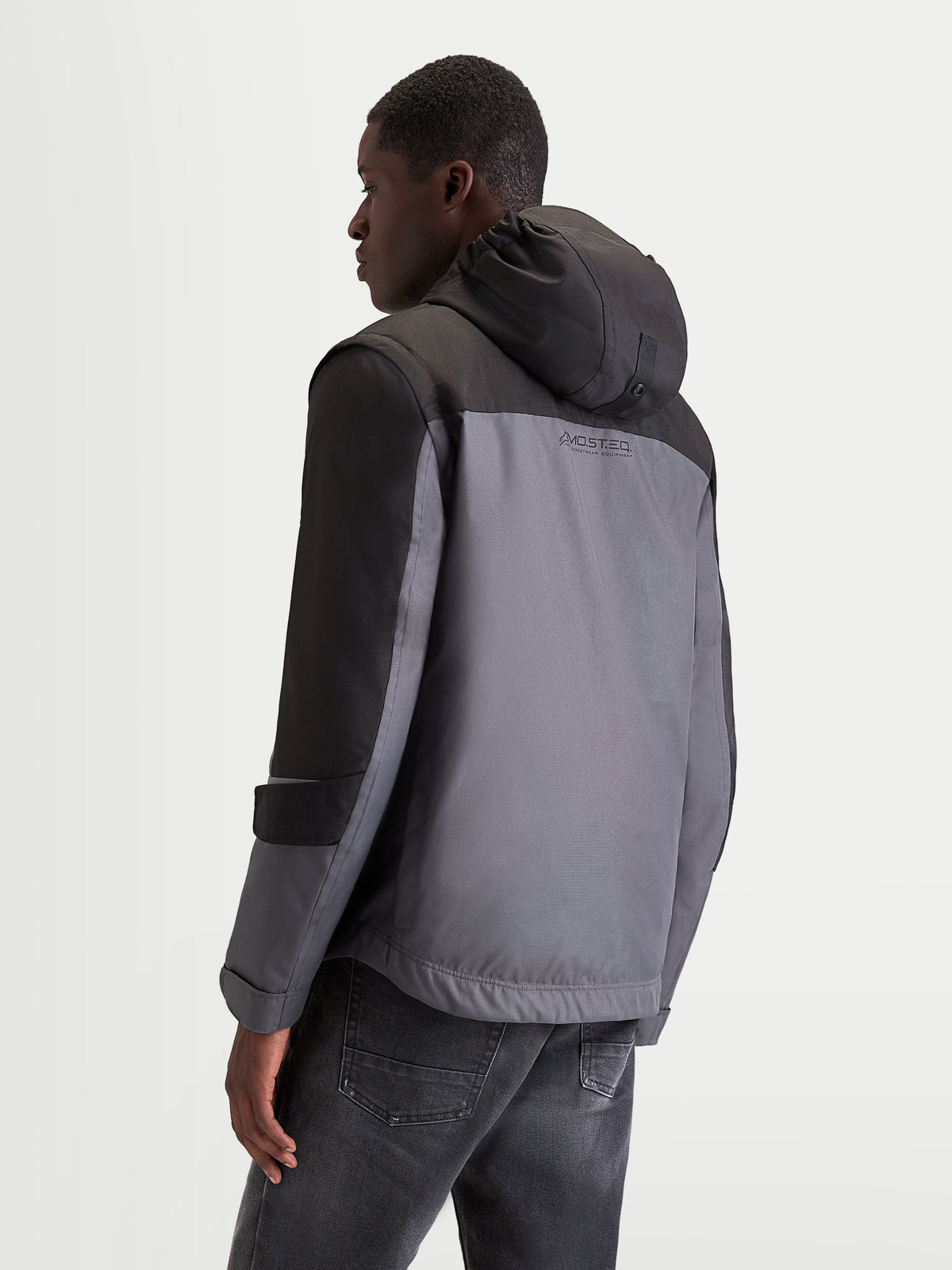 Alpinestars Morfex Parka WP, veste de moto urbaine pour homme en gris et noir, vue de profil arrière aux trois quarts montrant la capuche intégrée et la construction imperméable sur un modèle