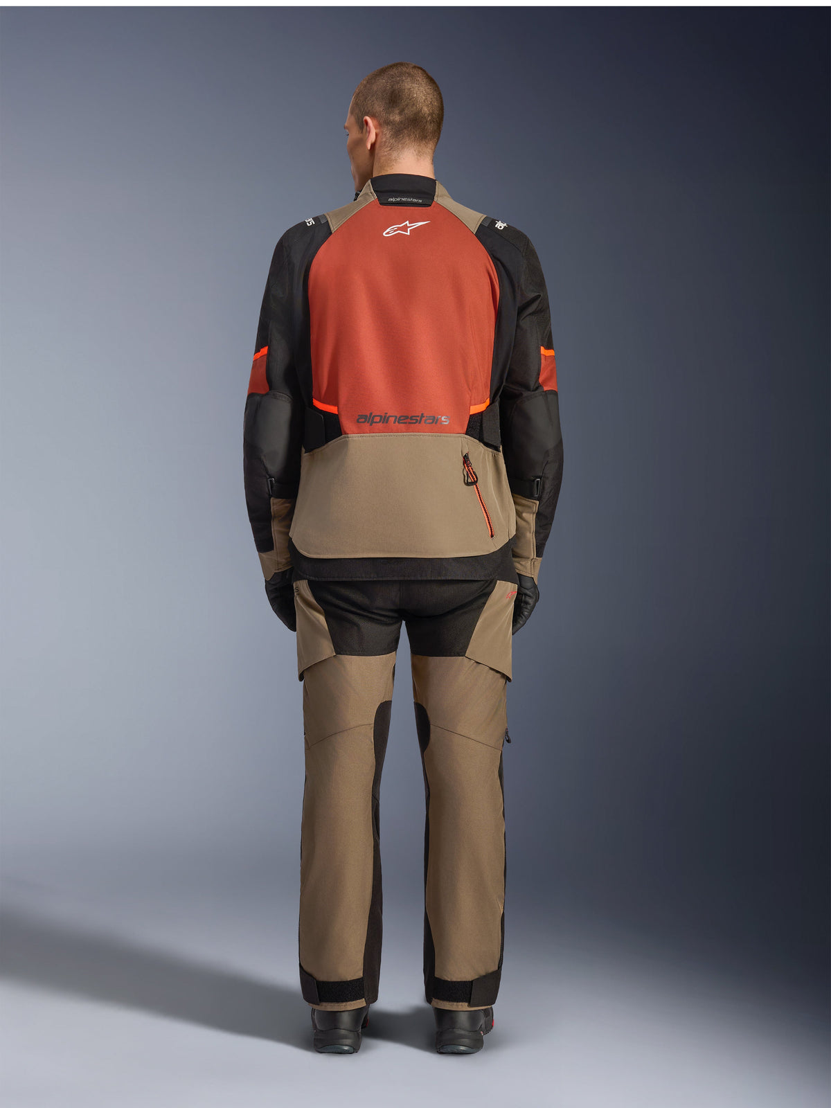 Veste Alpinestars Andes V4 Drystar®, Walnut Rust Black, vue arrière d'une veste de touring moto avec empiècement supérieur rouille et partie inférieure couleur noyer, portée avec un pantalon d'aventure assorti et des bottes noires