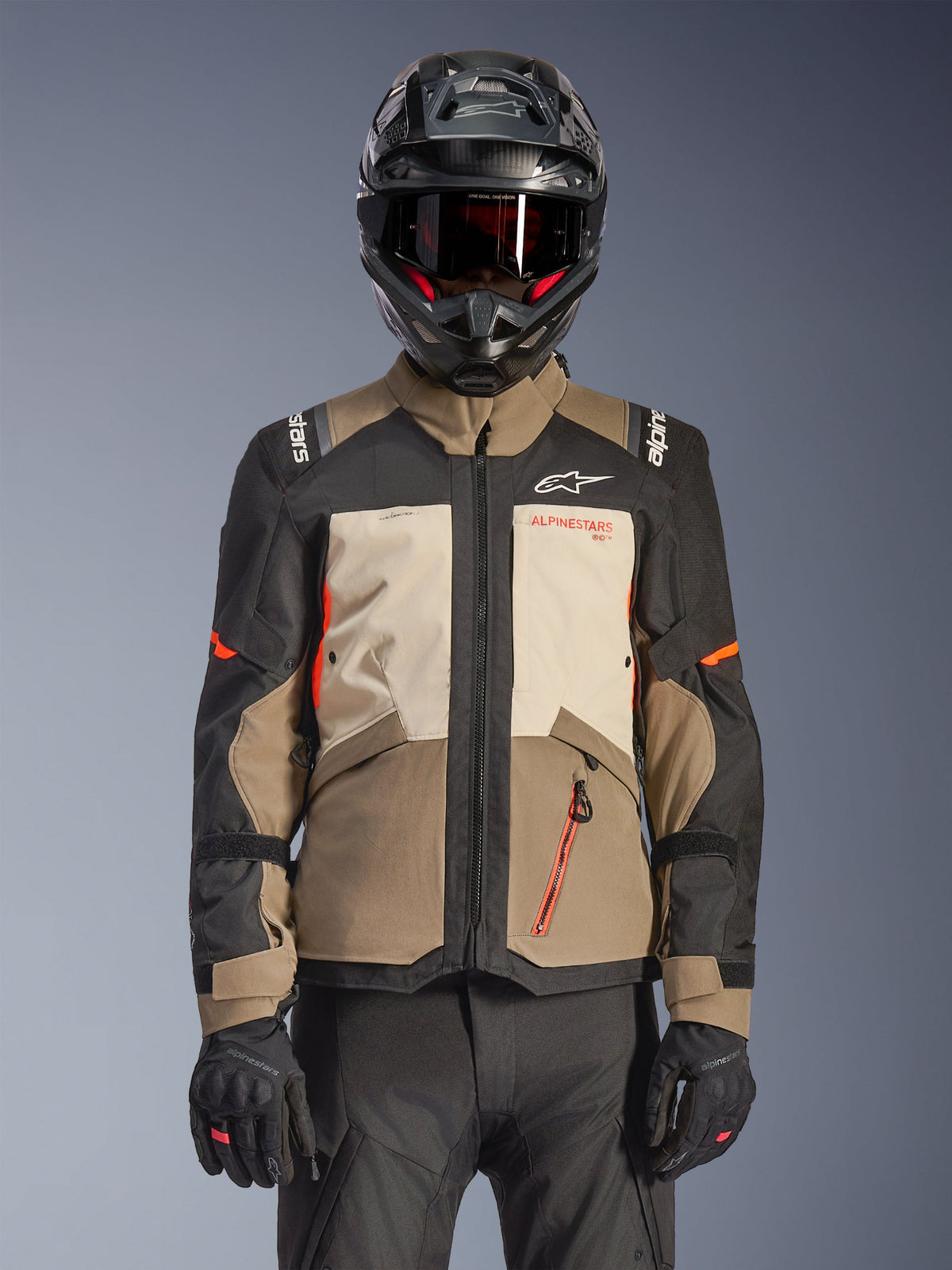 Veste Alpinestars Andes V4 Drystar®, Walnut Mastic Black, veste de touring aventure dotée d'empiècements marron noyer et crème mastic, de manches noires et d'accents orange vif, portée avec un casque de moto noir, un masque foncé et des gants noirs