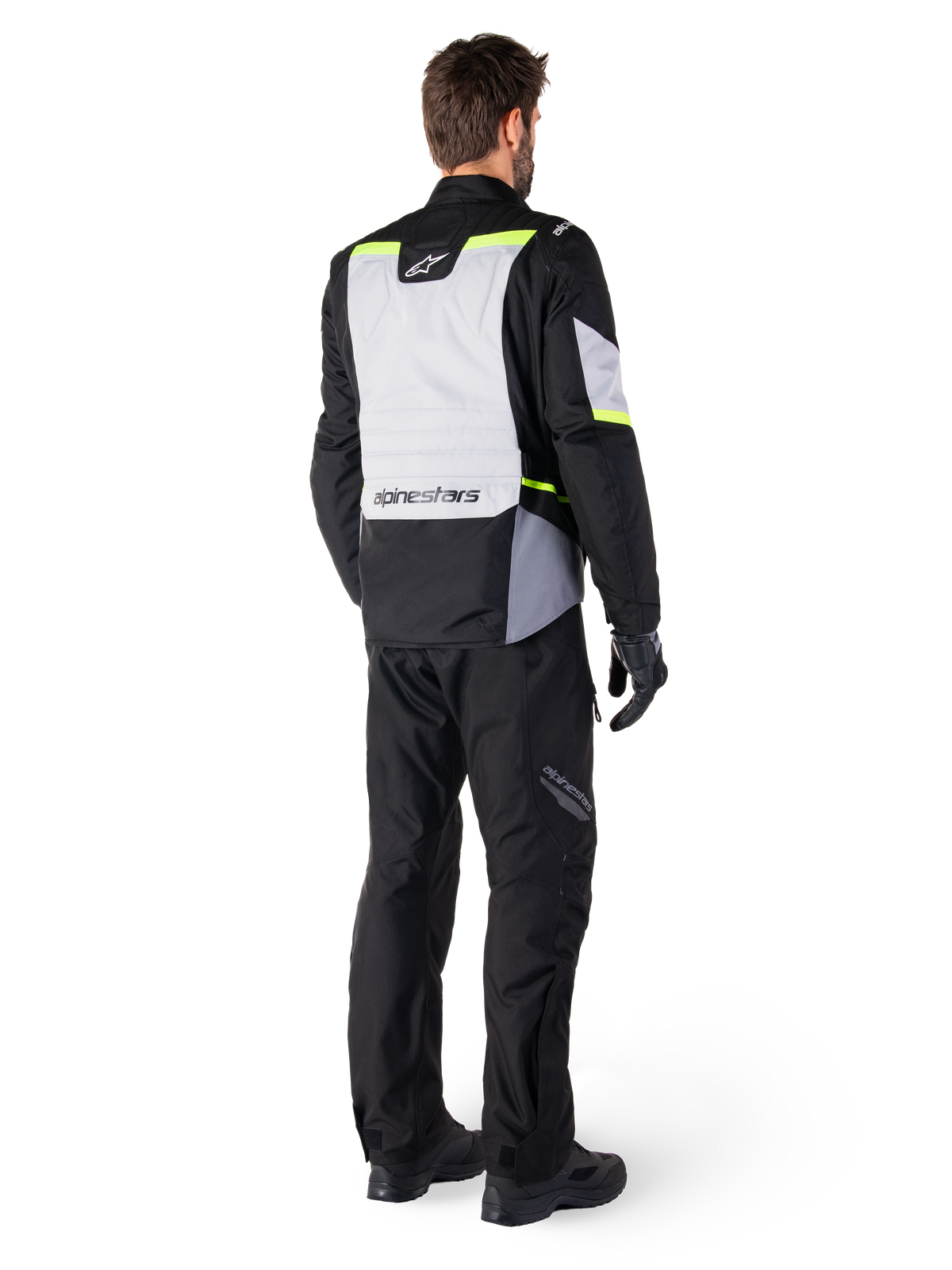 Alpinestars ST-1 Waterproof Jacket, adventure touring motorcycle jacket shown from the back, Ice Gray and Black with Yellow Fluo accents, worn with black riding pants and gloves, modern streamlined design with high-visibility fluorescent details and Alpinestars branding.