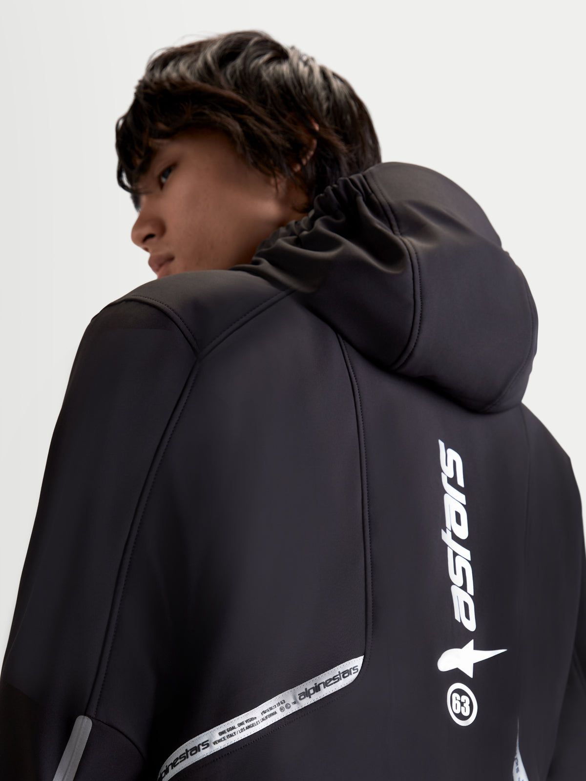 Alpinestars C-5 Drystar Jacket, men's urban contemporary motorcycle textile jacket in black, rear close-up view showing integrated hood and reflective branding details worn by a model