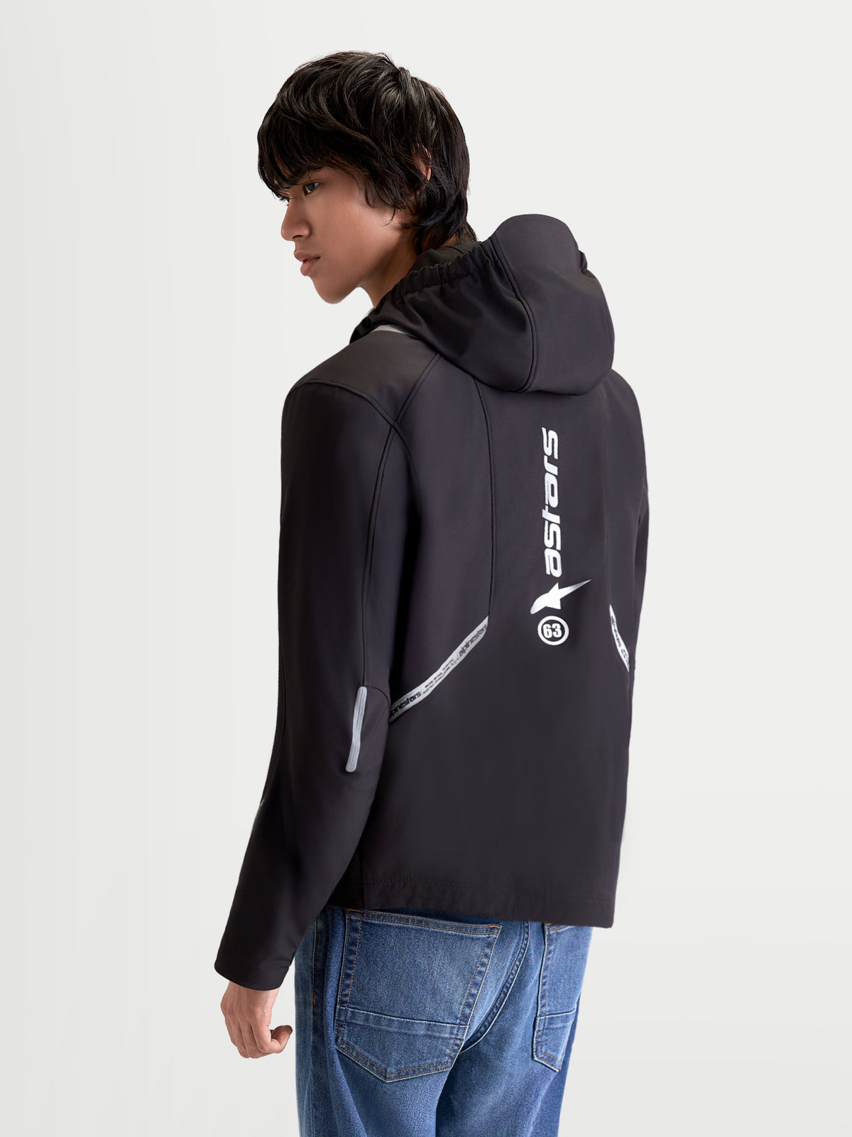 Alpinestars C 5 Drystar Veste, veste de moto urbaine pour homme en noir, vue arrière sur un modèle montrant la capuche intégrée, les détails réfléchissants et le logo vertical imprimé dans le dos