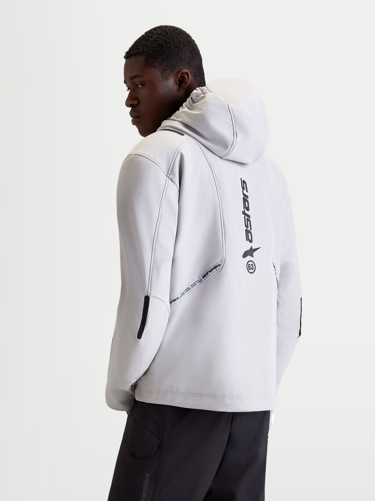Alpinestars C 5 Drystar Veste, veste de moto urbaine contemporaine pour homme en gris clair et noir, vue de dos sur un modèle montrant une capuche intégrée, une construction softshell et des détails de logo verticaux au dos