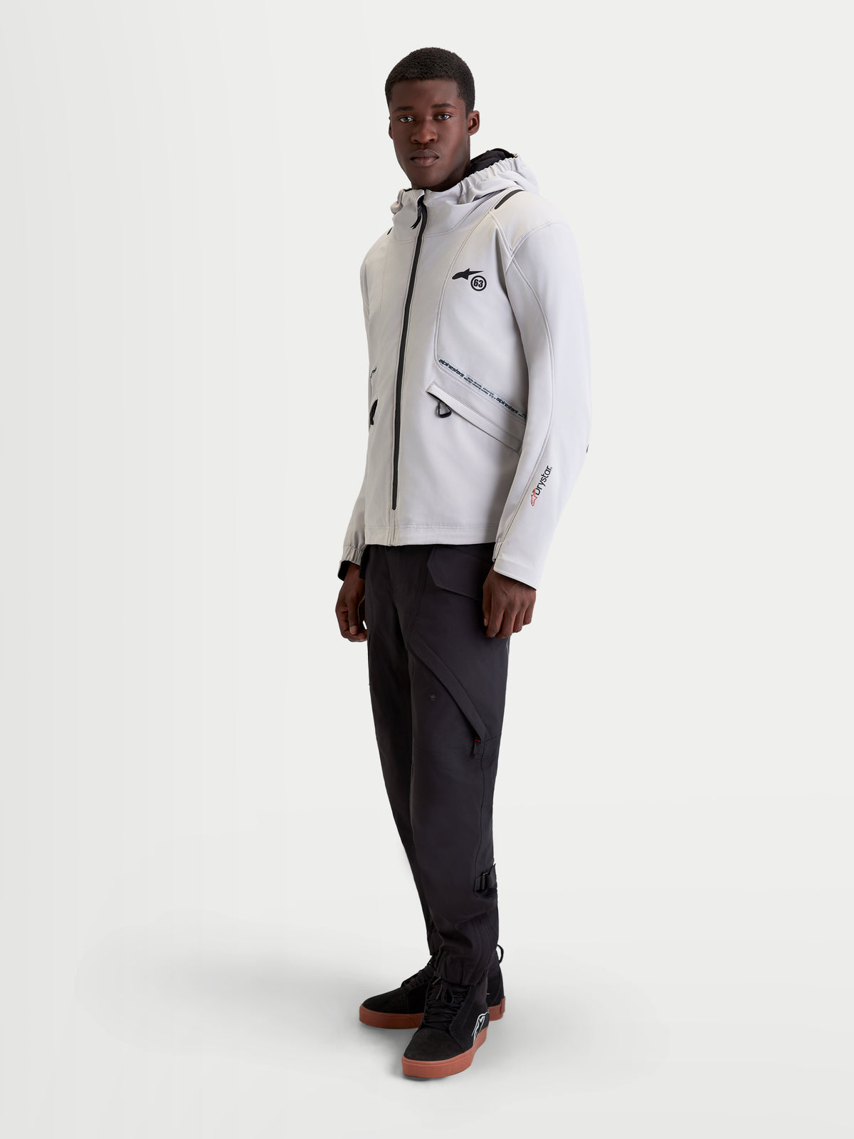 Alpinestars C 5 Drystar Veste, veste de moto urbaine pour homme en gris clair et noir, portée par un modèle mettant en valeur la construction softshell imperméable, la capuche intégrée et les éléments de protection