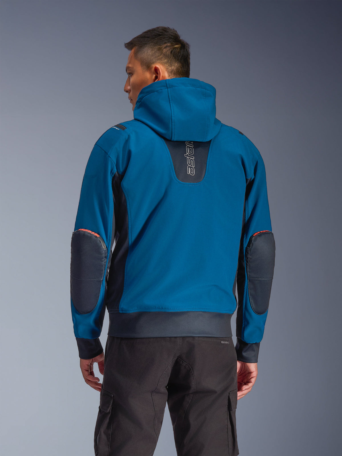 Veste imperméable Alpinestars Moblast, Dark Petrol et Dark Navy, hoodie de moto urbain vu de dos, doté d'une capuche fixe, logo 'astars' vertical sur le haut du dos, empiècements renforcés sombres aux coudes, taille et poignets élastiqués, vêtement de conduite technique moderne