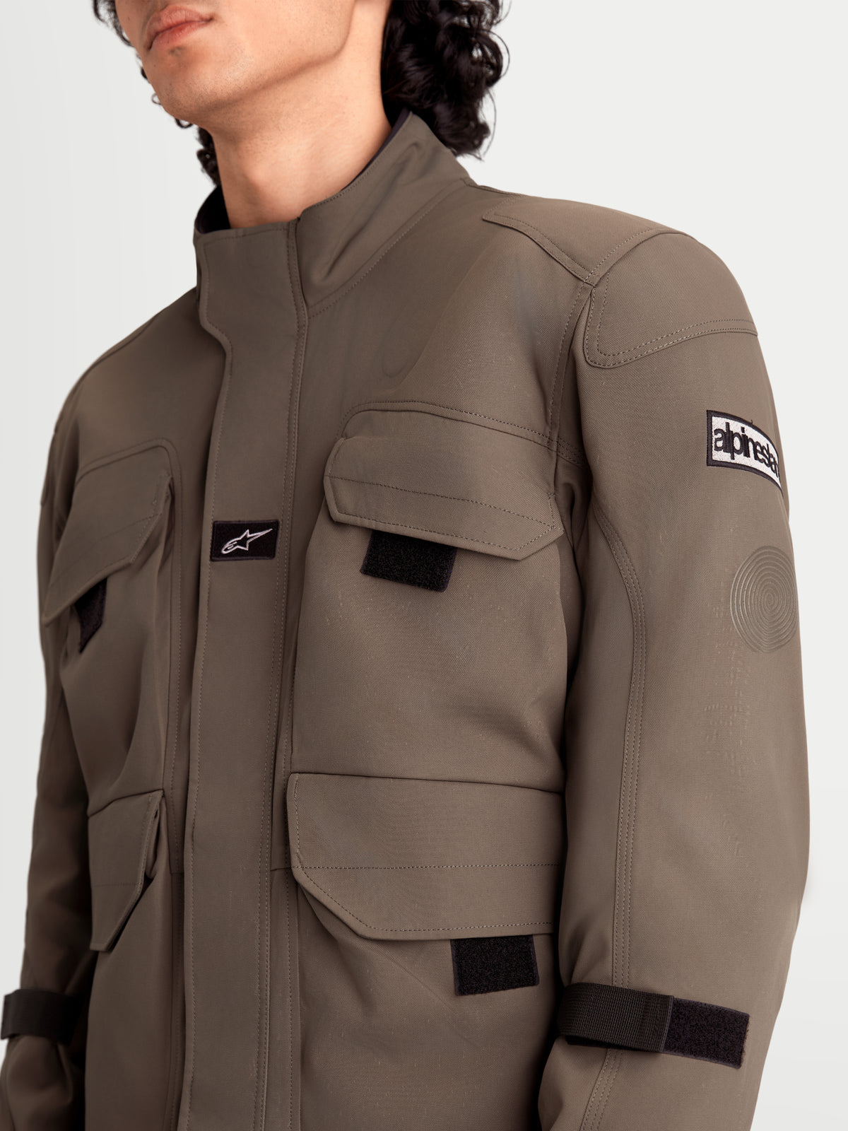 Alpinestars Veste Altan Drystar, veste de moto urbaine contemporaine pour homme en marron et noir, vue rapprochée montrant les poches cargo de style veste de terrain, la construction en poly-tissu mat et le détail des protections d'épaules portées par un modèle