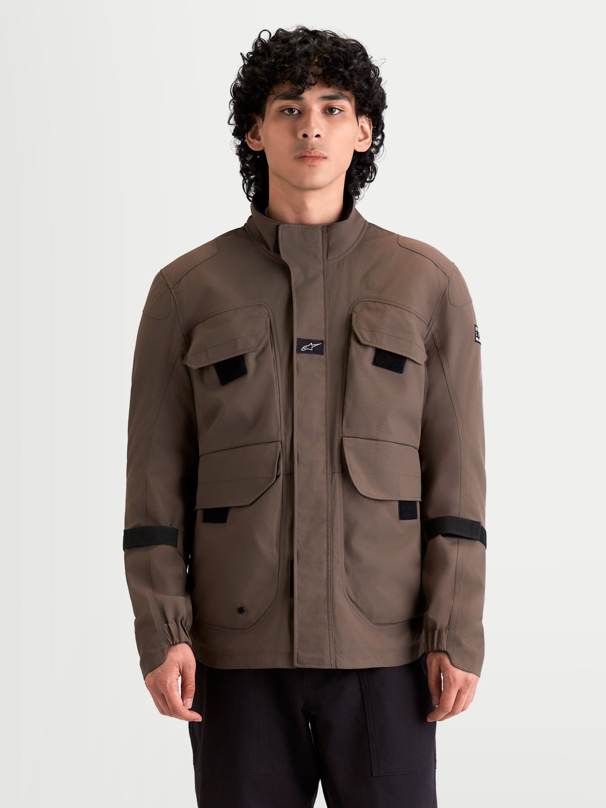 Alpinestars Altan Drystar Veste, veste de moto urbaine contemporaine pour homme marron, vue de face portée par un modèle montrant des poches de rangement de type veste de campagne et un col montant