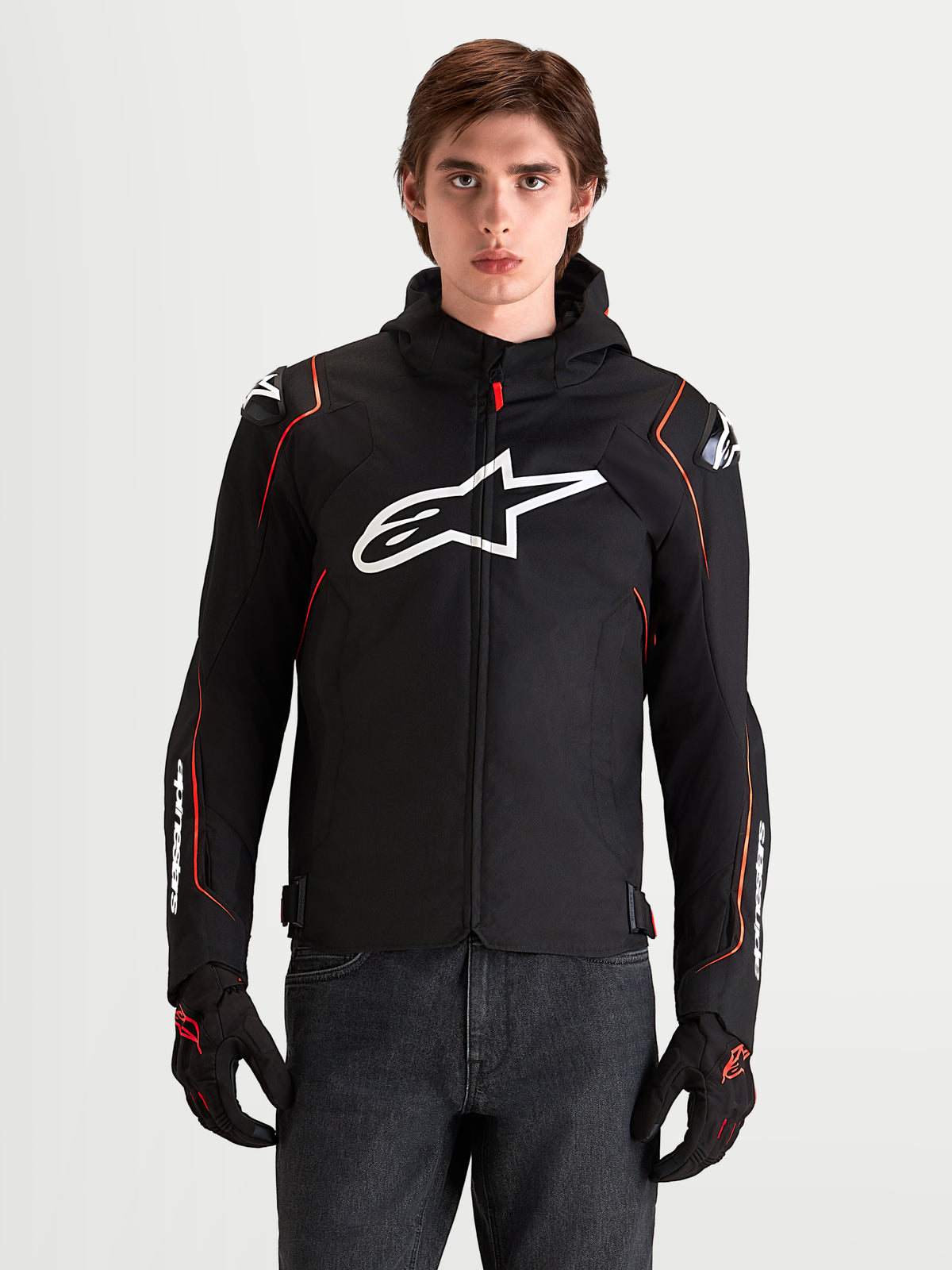 Alpinestars Zaca V 2 Waterproof Veste, veste de moto sport pour homme noire et rouge fluo, avec protections d'épaules DFS et logo Astar blanc sur la poitrine, portée par un modèle en studio