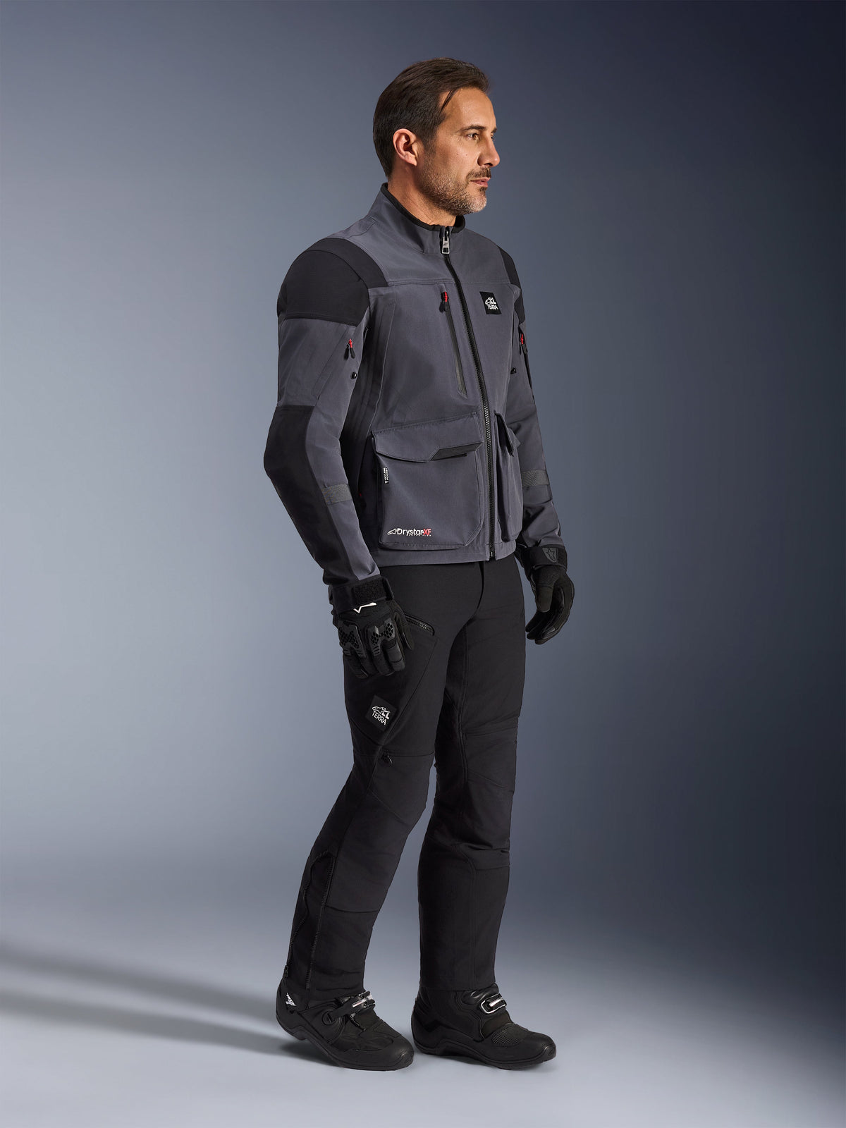 Alpinestars Maxdura Drystar®XF Laminated Armored Shell, Deep Gray and Black motorcycle jacket, technical dual-sport shell worn with matching black pants and boots, featuring cargo pockets and reinforced shoulder panels, studio shot of complete adventure riding gear