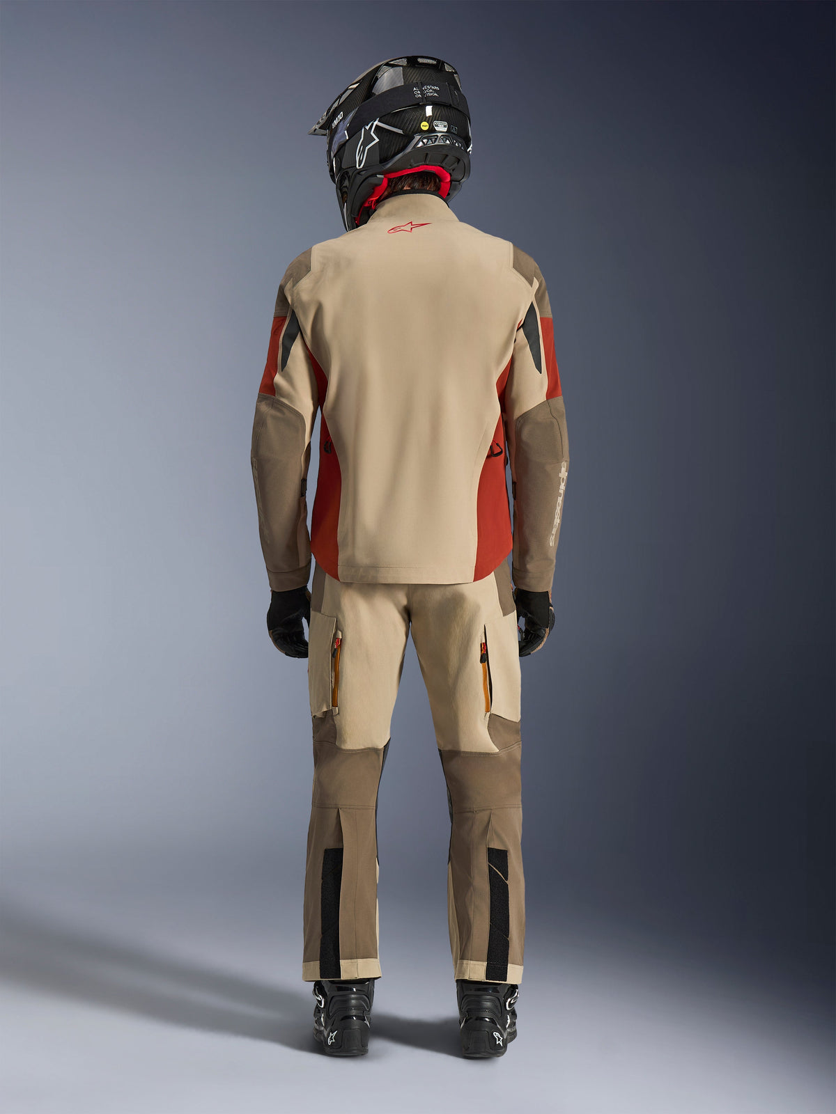 Alpinestars Maxdura Drystar®XF Laminated Armored Shell, veste et pantalon de moto d'aventure assortis, coloris Aluminum Walnut et Rust Brown, vue arrière d'un pilote avec casque et bottes noirs, équipement professionnel d'aventure-touring