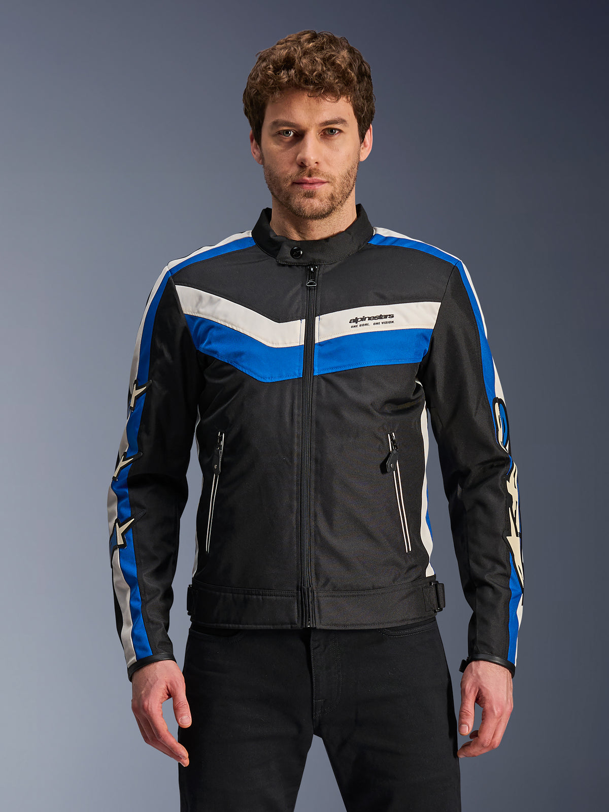 Alpinestars T-Dyno WR Jacket, veste de moto en textile pour homme, noire avec des bandes bleues et blanc écru, motif en chevron sur la poitrine et logos étoiles sur les manches, fermeture éclair frontale et poches zippées, équipement urbain d'inspiration vintage