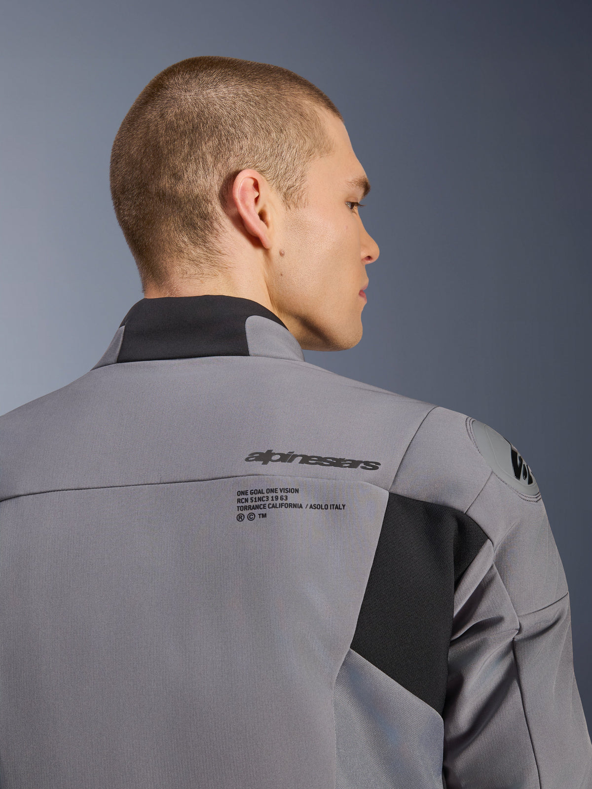 Veste imperméable Alpinestars SMX en Dark Gray Black, gros plan du dos et de l'épaule montrant le logo Alpinestars et la protection d'épaule DFS lite, portée par un mannequin homme