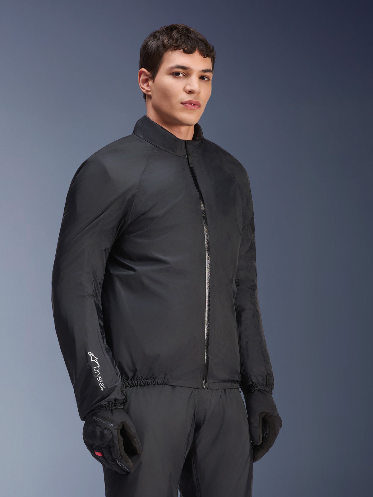 Membrane imperméable de la veste Alpinestars Andes Air Drystar®, noire, portée par un mannequin homme avec des gants et un pantalon noirs, textile technique léger avec marquage 'Drystar' sur la manche, prise de vue en studio