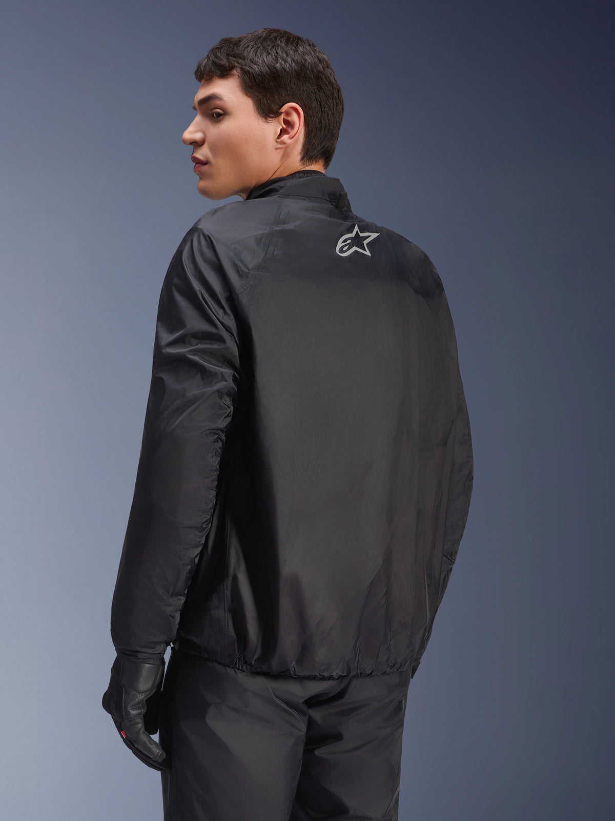 Veste Alpinestars Andes Air Drystar®, membrane imperméable amovible noire, vue de dos sur un modèle masculin, avec un petit logo Alpinestars blanc sur le haut du dos, associée à des gants de moto noirs