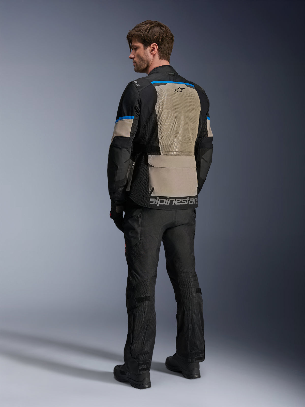 Alpinestars Andes Air Drystar® Jacket, Black Laurel Gray and Bright Blue, rear view showing large mesh ventilation panel on the back, logo on lower hem, worn with black motorcycle pants and boots.