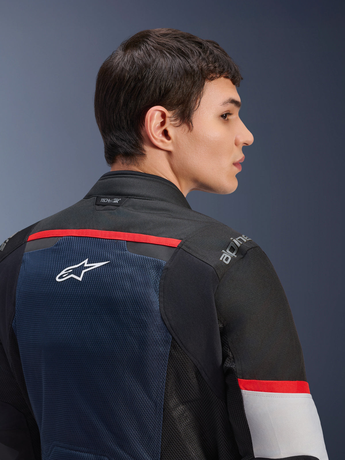 Veste Alpinestars Andes Air Drystar®, Bleu Profond Noir et Gris Glacé, vue de dos rapprochée sur un mannequin, dotée d'un panneau en maille respirante avec logo étoile blanc, accents rouges et marquage Tech-Air® sur le col, équipement de moto touring deux saisons
