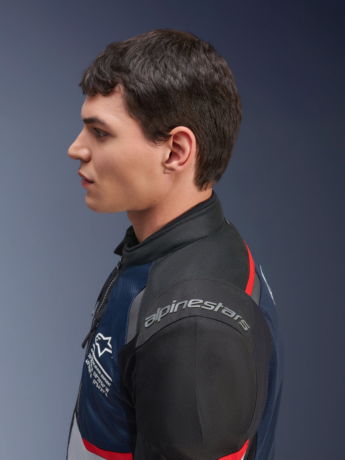 Veste Alpinestars Andes Air Drystar®, coloris Deep Blue Black Ice Gray, profil latéral d'un mannequin portant la veste textile en mesh, avec logo Alpinestars sur l'épaule et accents rouges, équipement de touring deux saisons