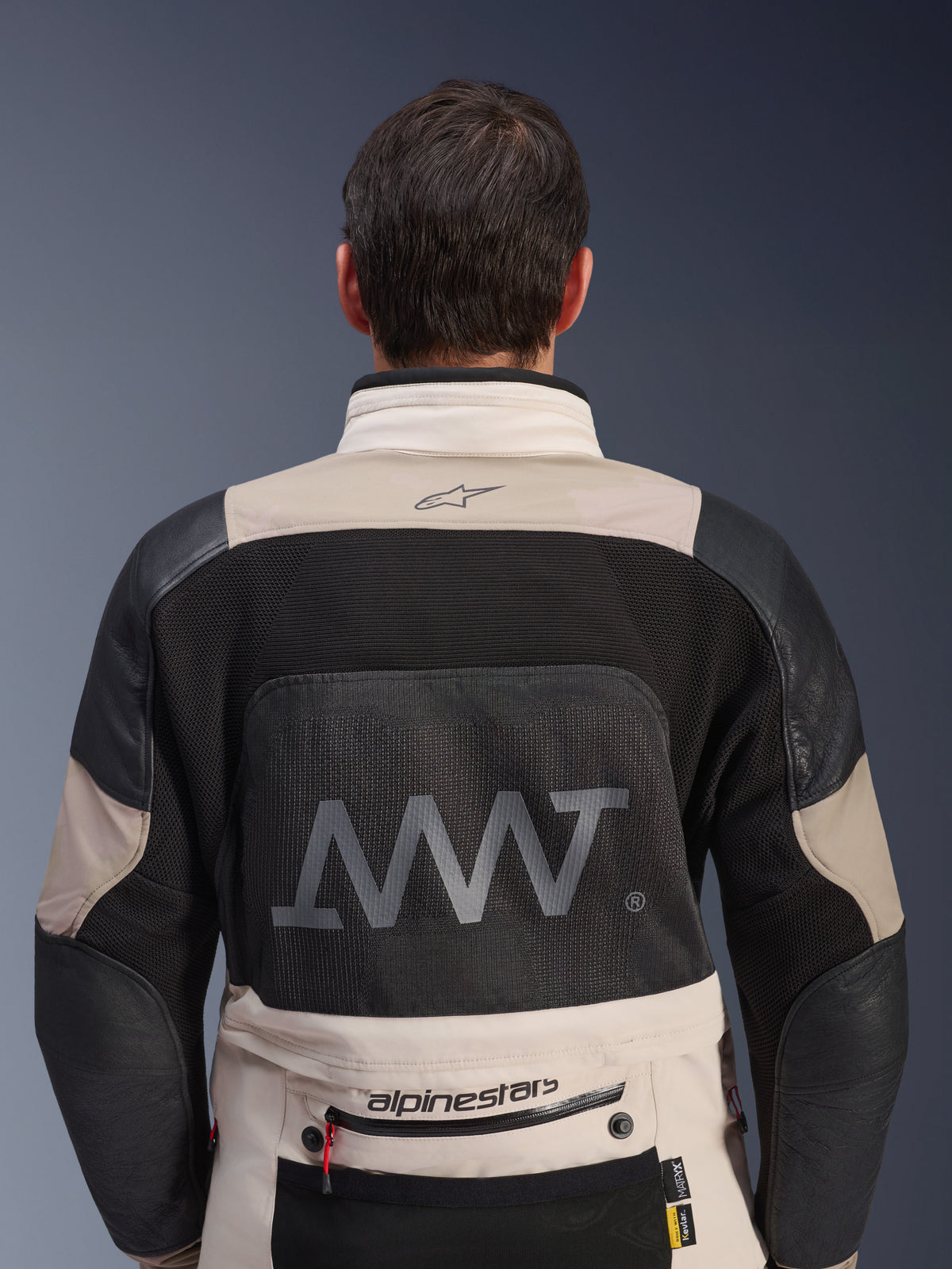 Vue arrière de la veste Alpinestars AMT-10LAB Drystar® XF en White Sand et noir, avec un grand logo AMT sur le panneau dorsal en mesh, marquage Alpinestars en bas du dos et construction textile technique pour la moto d'aventure
