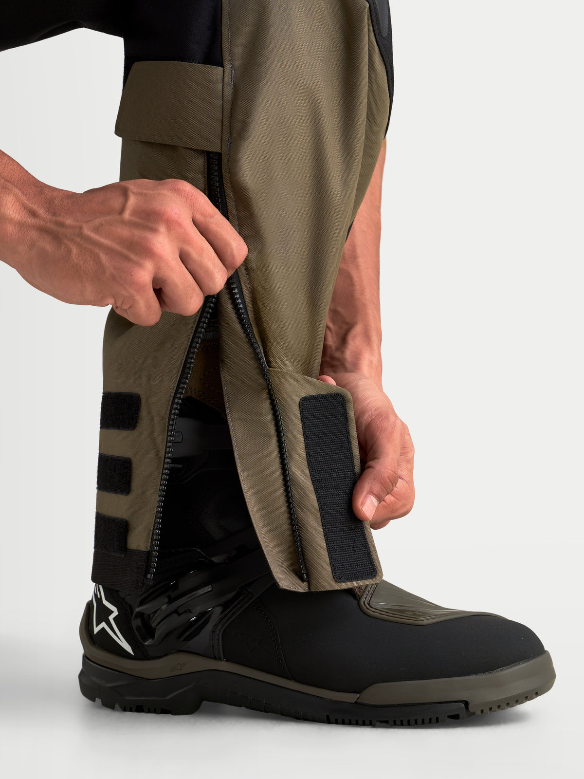 Pantalons Alpinestars Harok V2 Drystar, pantalon d'aventure pour moto, marron et noir, vue détaillée de la fermeture éclair sur la jambe et de la construction par-dessus les bottes