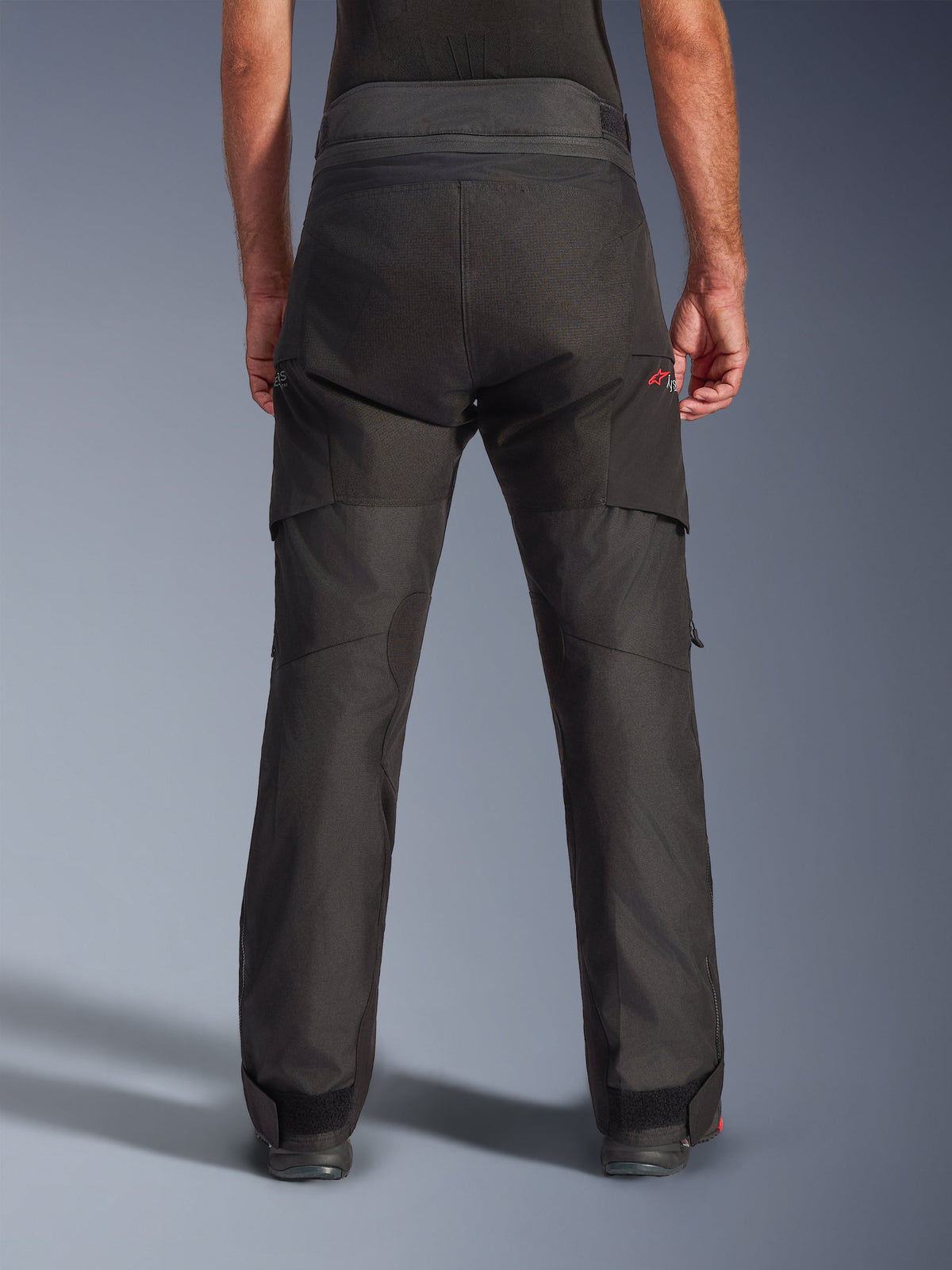 Pantalon Alpinestars Andes V4 Drystar® - Long, pantalon de moto d'aventure noir, vue arrière, doté de panneaux d'assise renforcés, d'un logo Astar rouge et de sangles de cheville ajustables pour un maintien optimal.