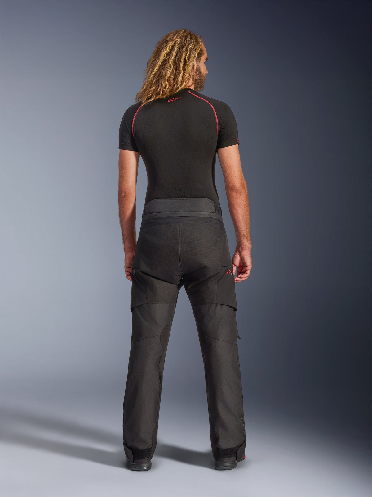 Pantalon Alpinestars Andes V4 Drystar®, pantalon de moto d'aventure, noir, vue arrière porté par un mannequin avec une couche de base noire, doté d'une construction textile durable et de renforts ripstop pour une conduite par tous les temps