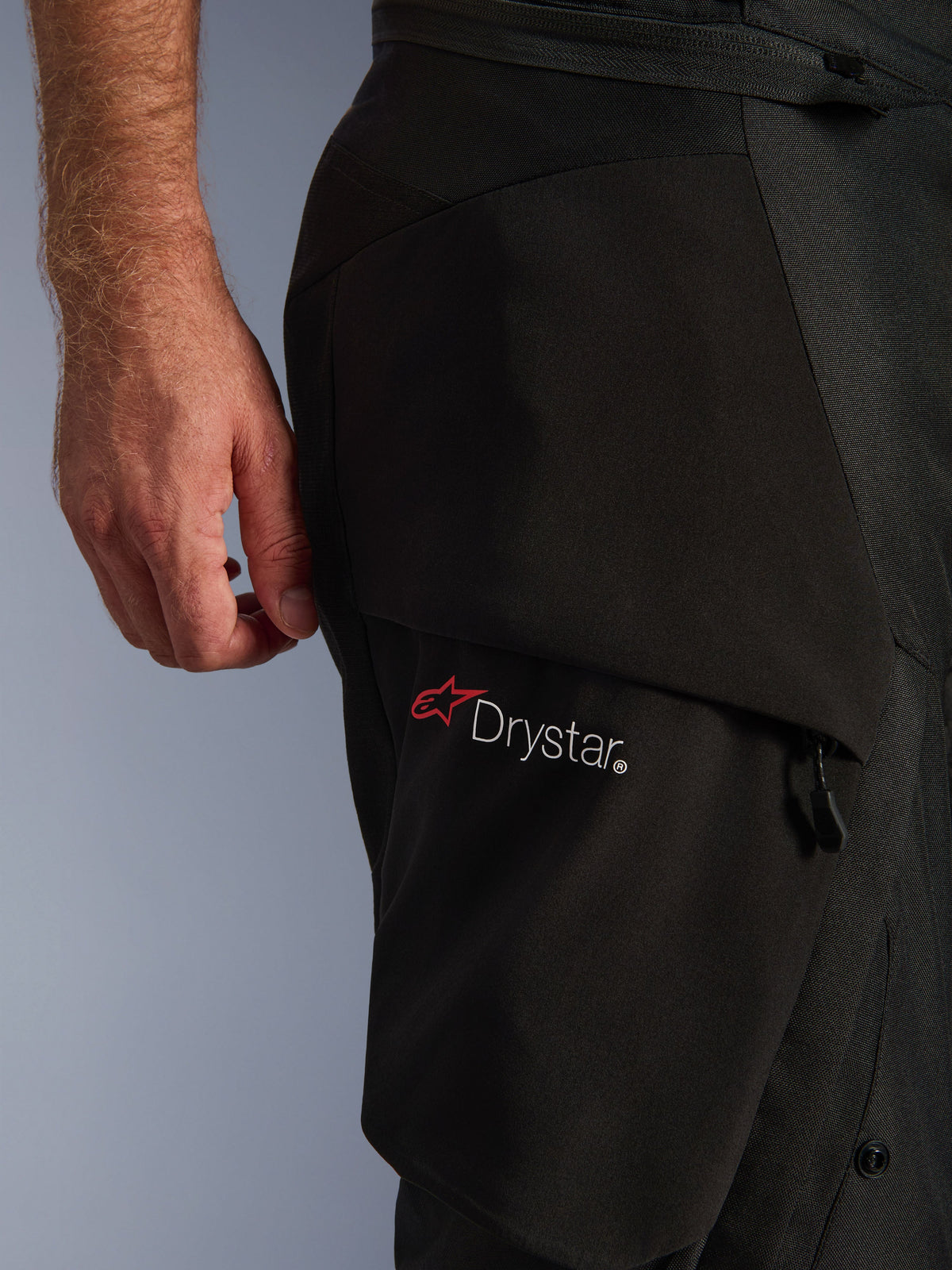 Pantalon Alpinestars Andes V4 Drystar®, noir, gros plan de la cuisse montrant le logo Drystar® sur une poche cargo, textile technique avec panneaux renforcés, pantalon de moto d'aventure imperméable