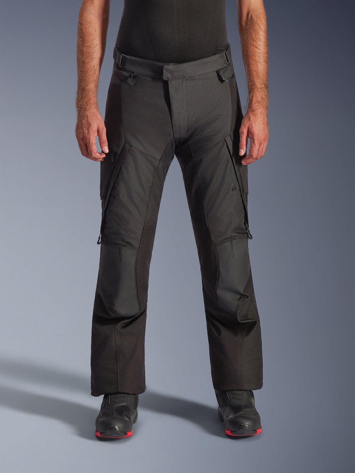 Alpinestars Andes V4 Drystar® Pants - Long, pantalon de moto adventure touring, noir, vue de face montrant la construction textile avec des poches cargo, des genoux renforcés et une taille ajustable, porté avec des bottes de moto noires, conçu pour une protection imperméable par tous les temps
