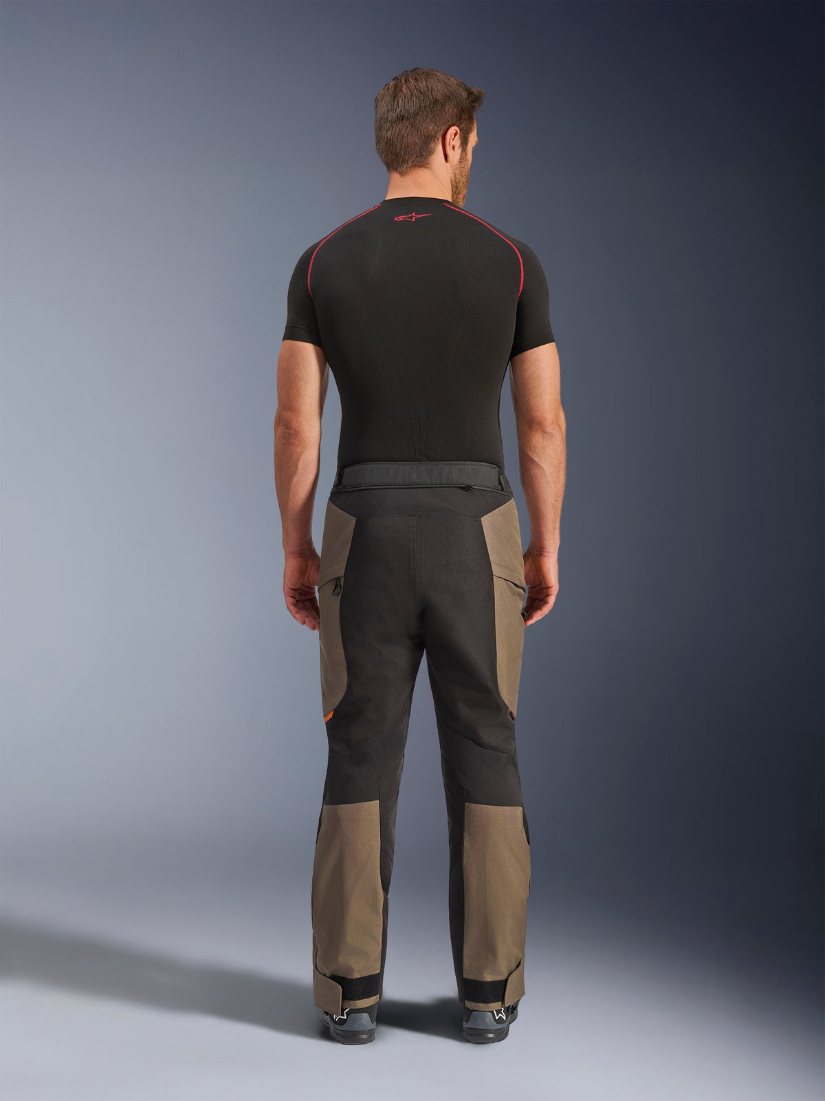 Alpinestars Cusco Drystar® Pants, pantalon de moto aventure, Walnut Black, vue de dos montrant des empiècements marron et noirs, construction en ripstop durable, porté avec un haut de couche de base noir