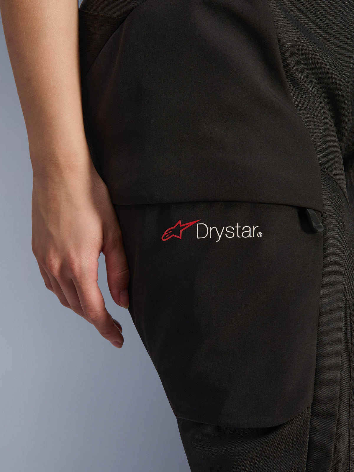 Alpinestars Stella Andes V4 Drystar® pour femme, pantalon de moto d'aventure, noir, gros plan sur la zone de la cuisse montrant le logo Drystar et l'icône de l'étoile rouge, textile résistant avec poche cargo et détail de fermeture éclair